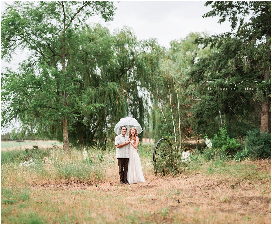 A Brenizer composite image of the bride and groom on the ranch, standing up a clear umbrella. 