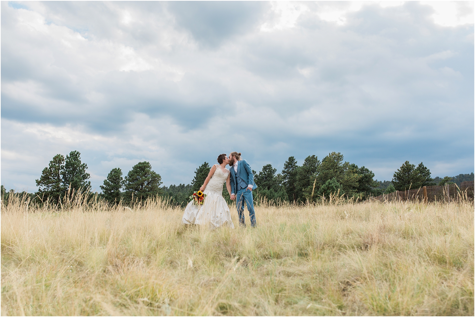 A gorgeous Colorado free-spirited wedding couple kisses below some dramatic looking skies in Evergreen! 