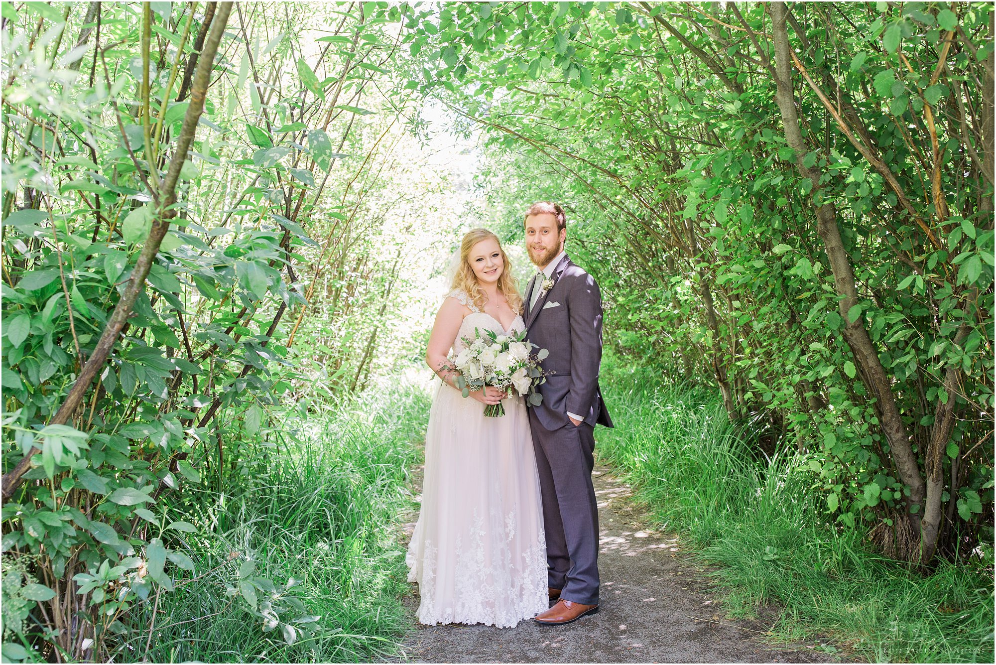 A beautiful natural green archway creates pretty portraits for the happy wedding couple in Bend, OR. | Erica Swantek Photography