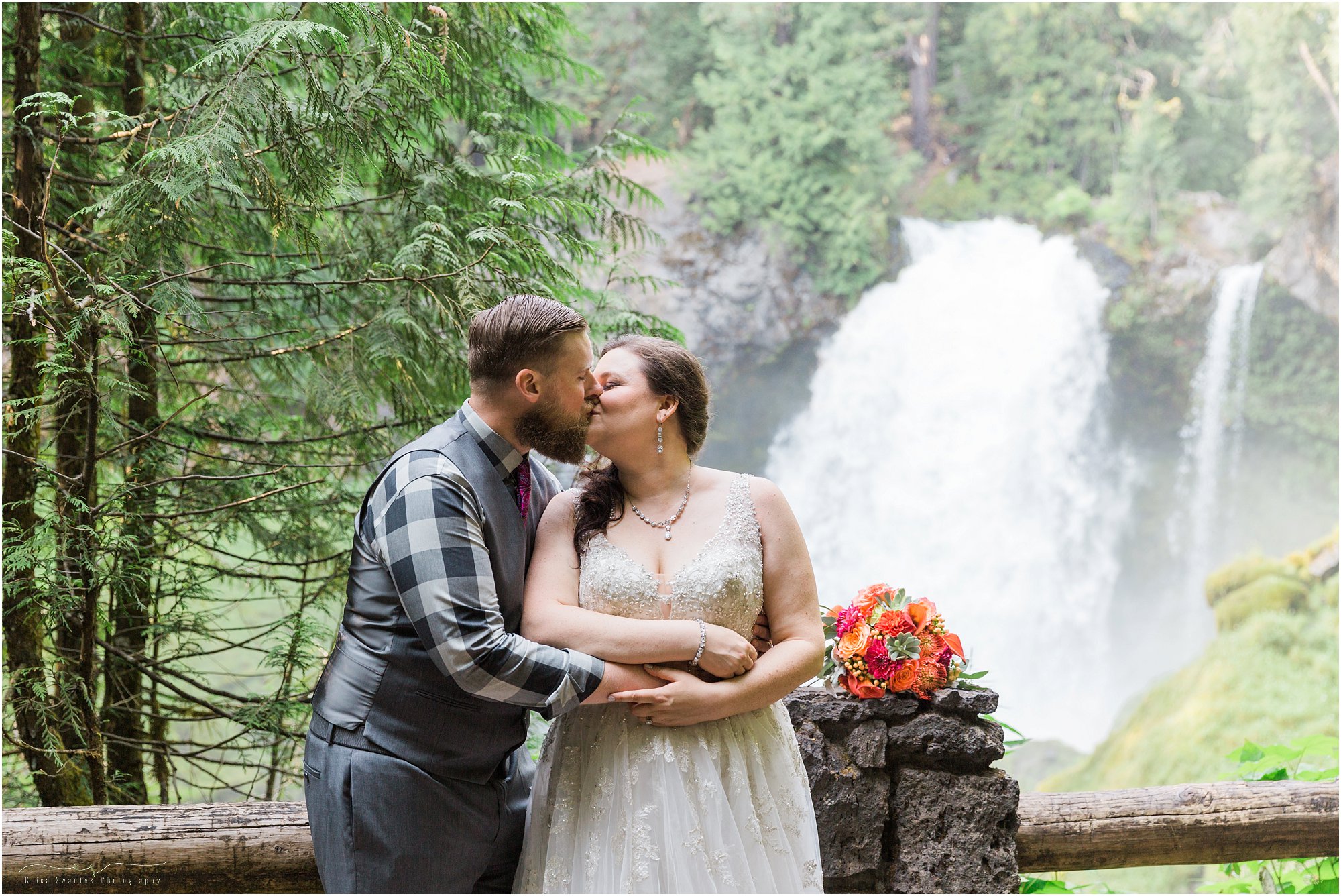A couple kisses in front of Sahalie Falls after their wedding ceremony in Oregon. | Erica Swantek Photography