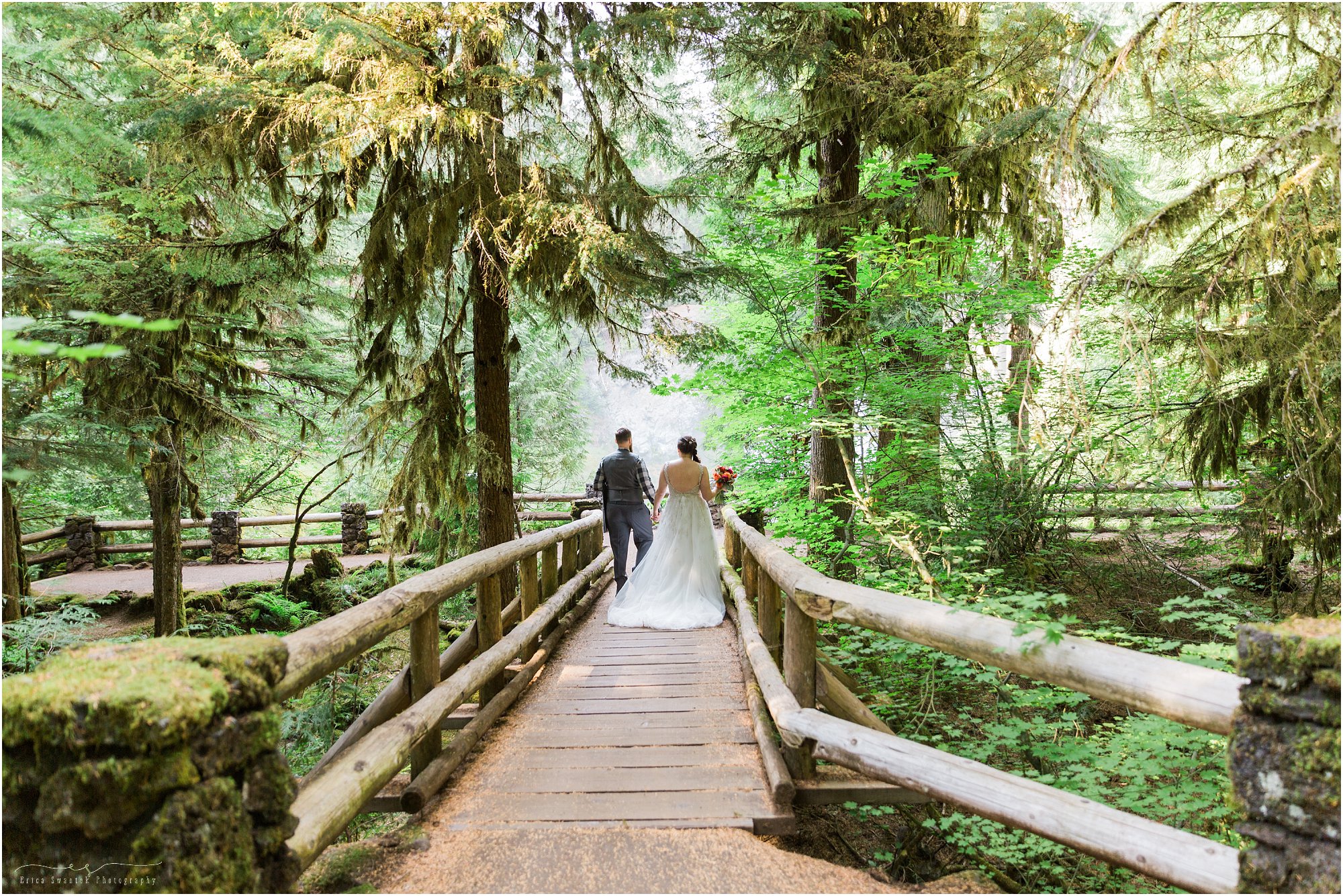 A couple strolls along the wooden bridge after their wedding at Sahalie Falls in Oregon captured by Bend wedding photographer Erica Swantek Photography. 