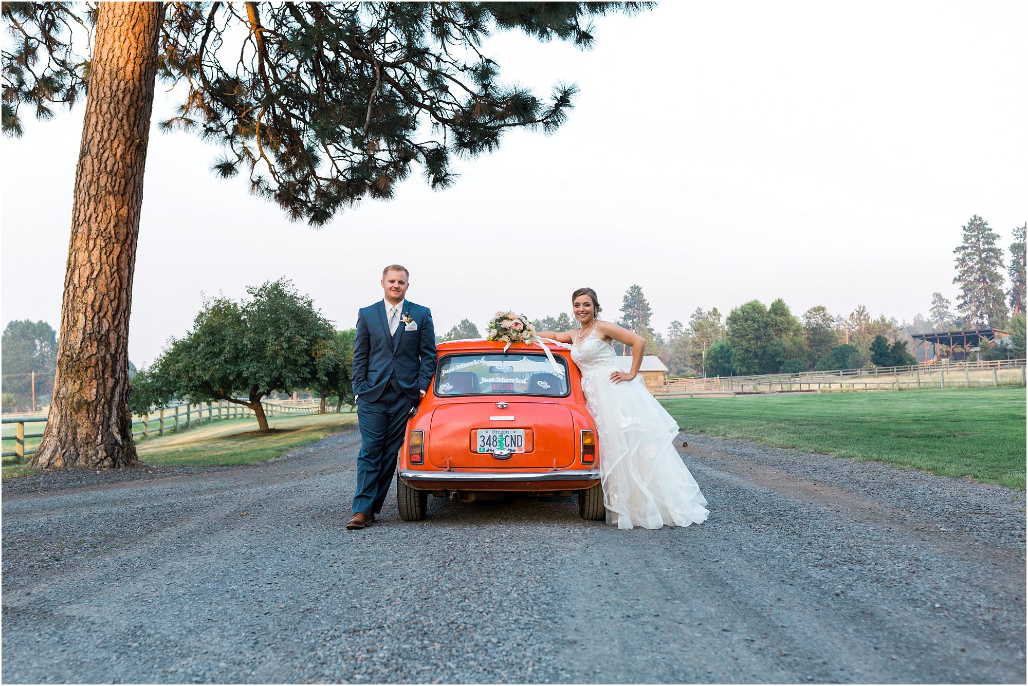 A couple poses in front of their fun wedding day getaway car at Bend, Oregon's Rock Springs Ranch wedding venue. | Erica Swantek Photography