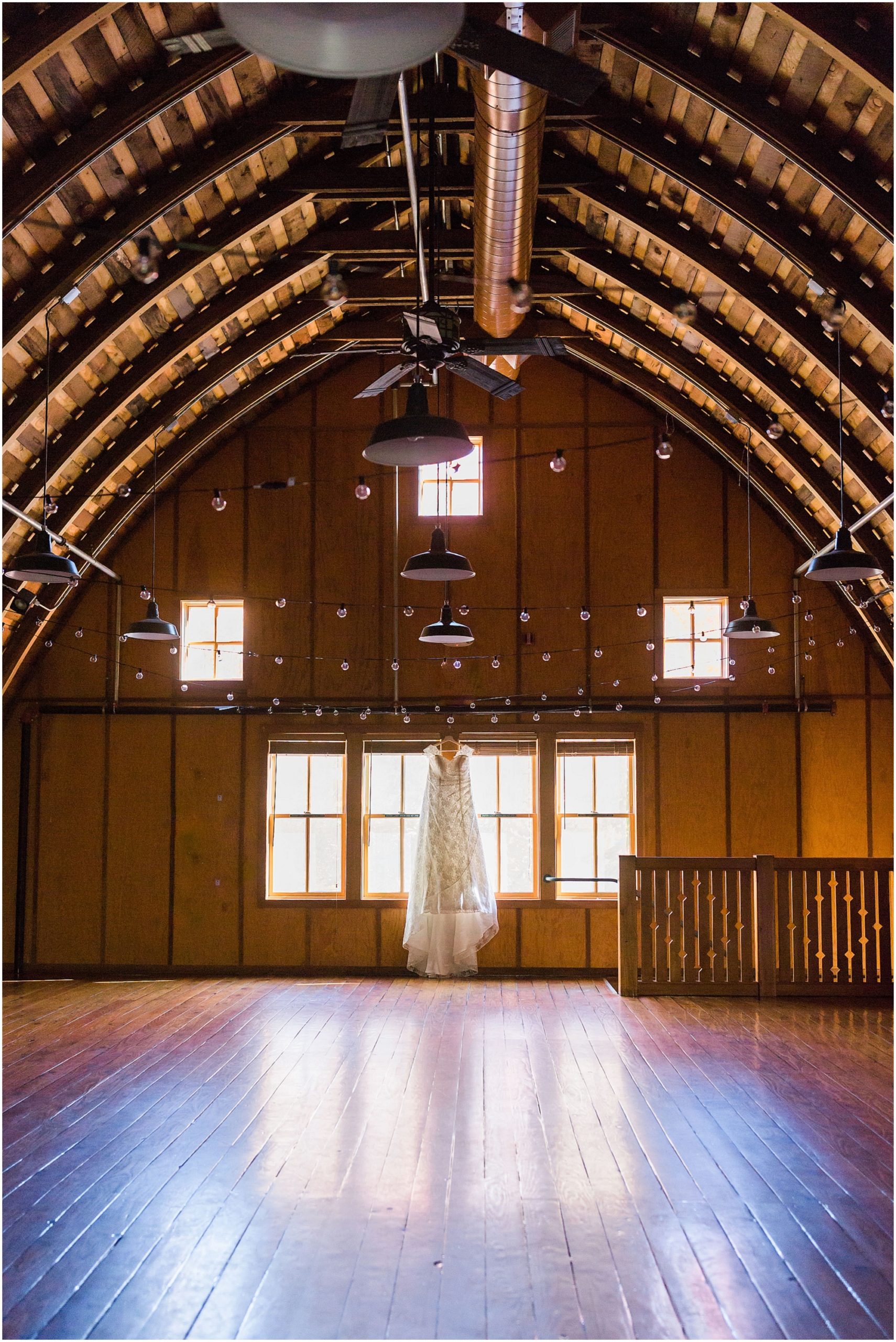 A gorgeous bride's dress hangs from the windows of the historic Hollinshead Barn wedding venue in Bend, OR. | Erica Swantek Photography