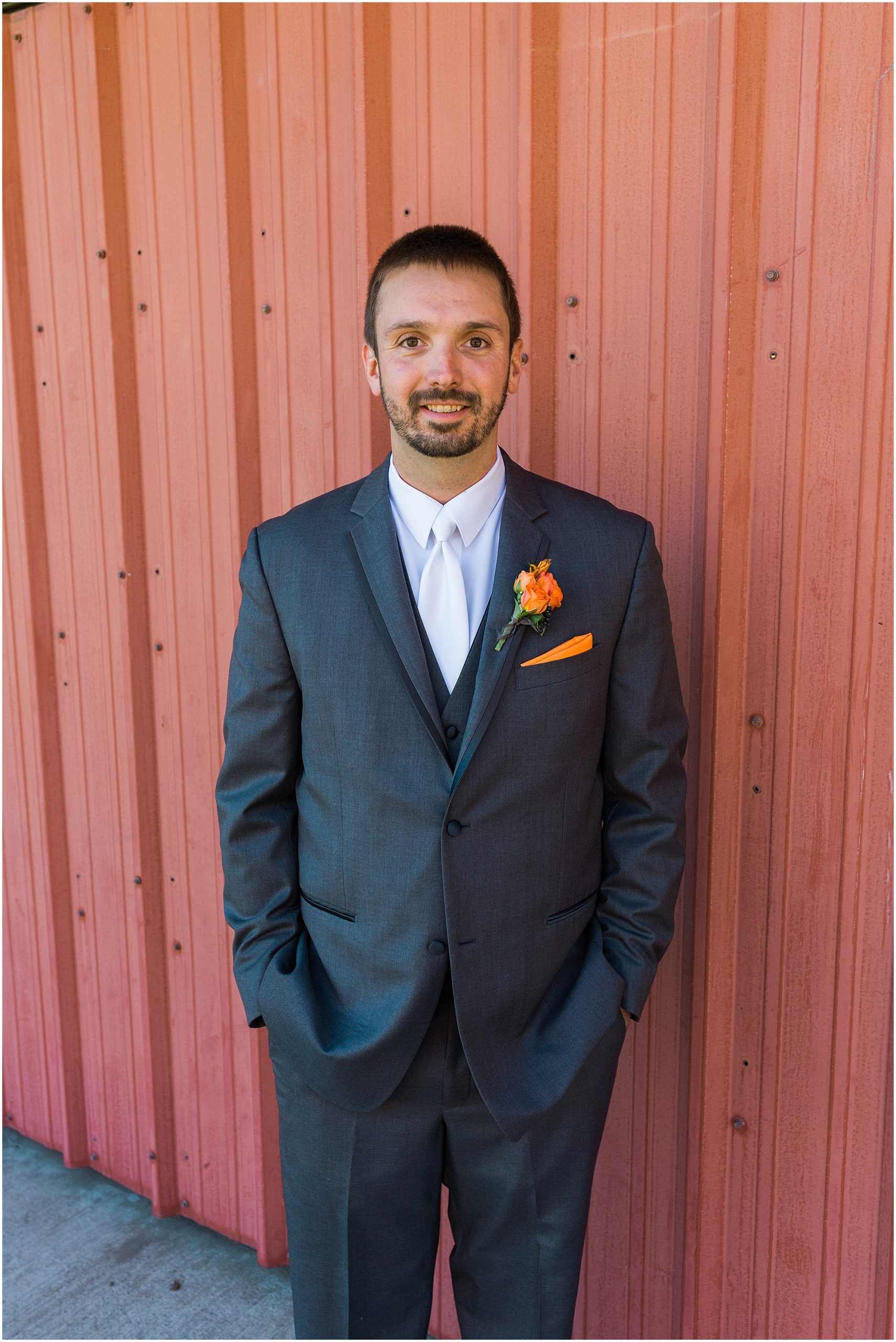 This handsome groom poses in front of the red metal doors at the Hollinshead Barn Fall wedding venue in Bend, OR. | Erica Swantek Photography