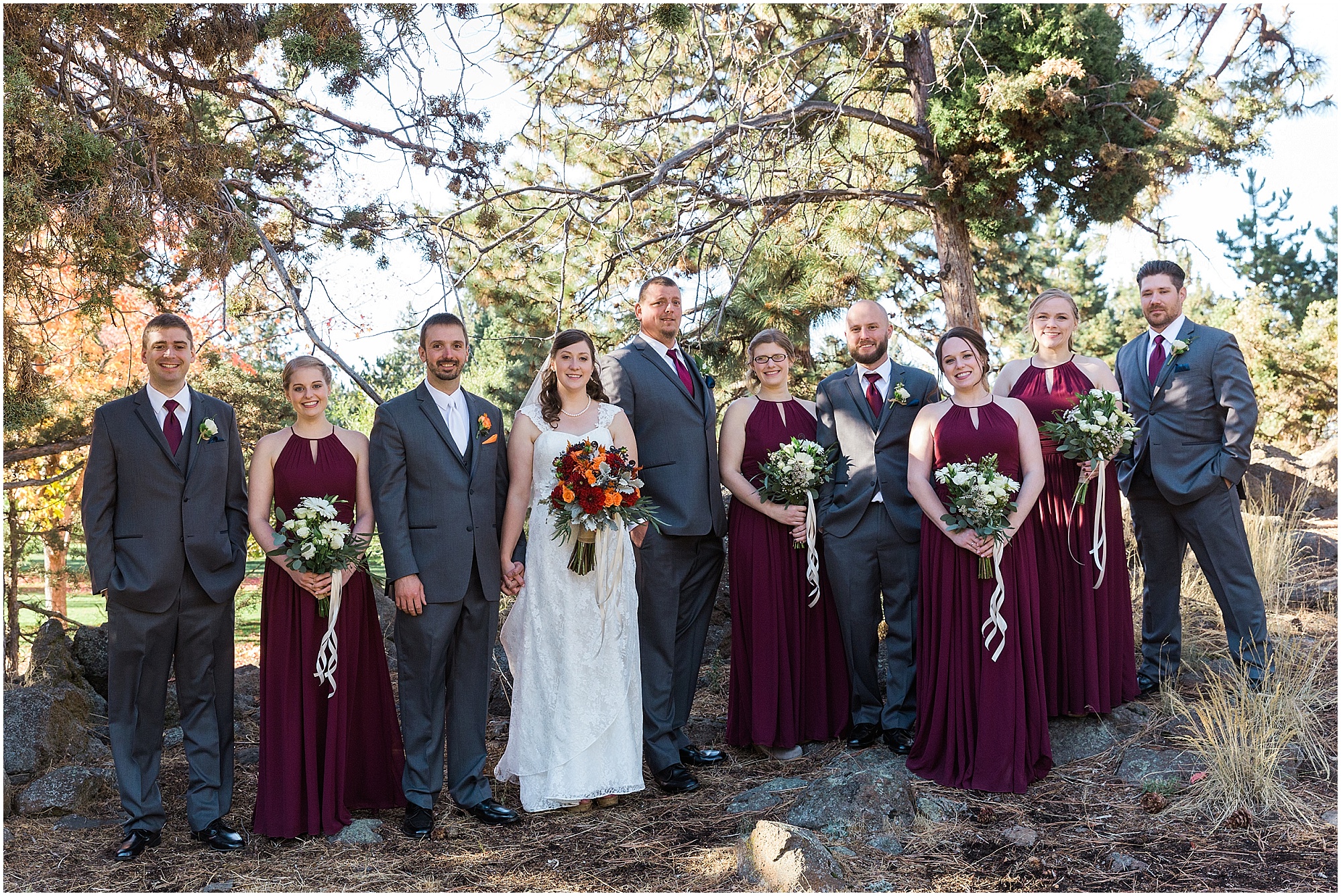 A gorgeous wedding party, wearing navy and maroon, pose for formal portraits at this outdoor Bend Oregon wedding at Hollinshead Park. | Erica Swantek Photography