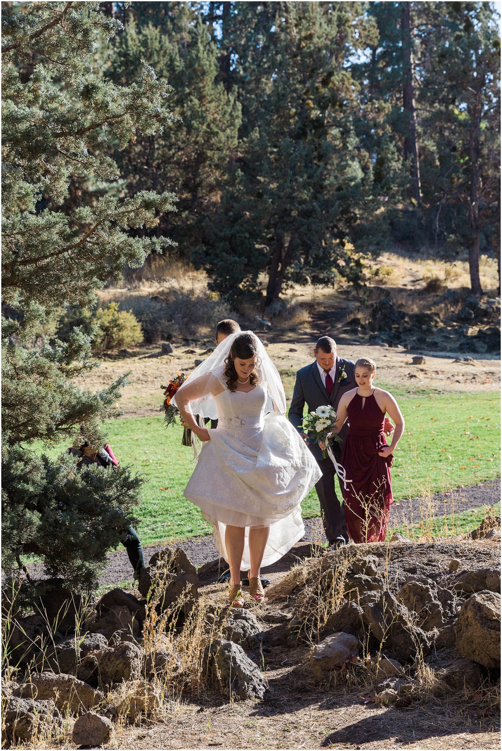 The bride hikes up her dress and walks through the lava rock at her Hollinshead Barn fall wedding in Bend, OR. | Erica Swantek Photography