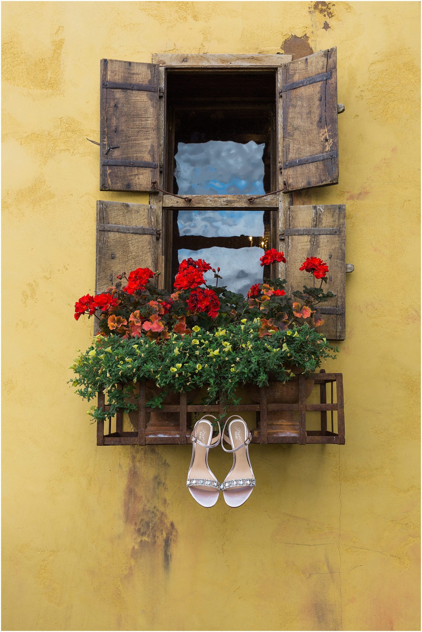 A beautiful window with flower pots and barnwood shutters is the perfect spot to hang a bride's shoes at the Tuscan inspired Ranch at the Canyons wedding venue in Bend, OR. | Erica Swantek Photography