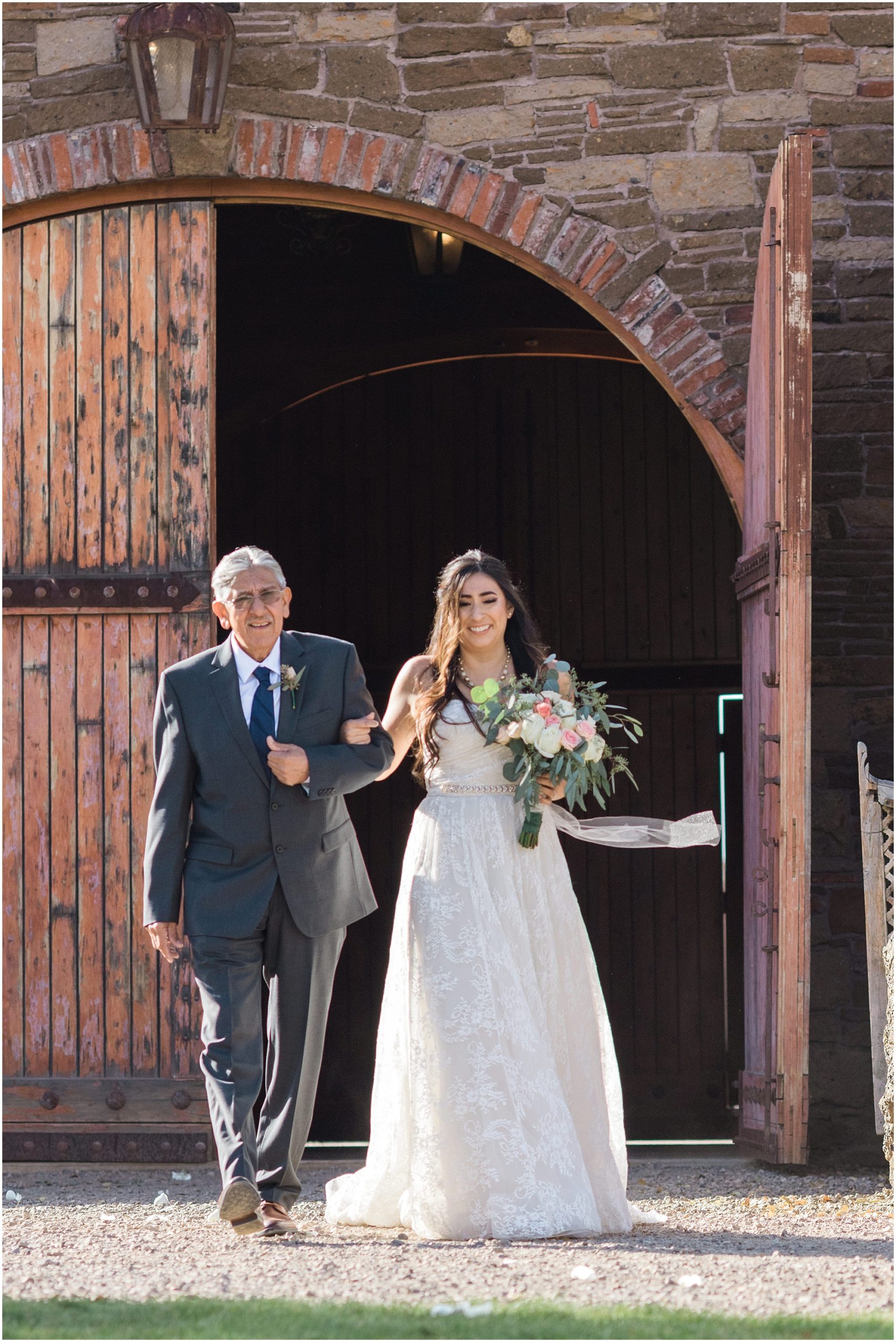 The bride and her father make their way out of the gorgeous barn wood doors at the Tuscan Stables wedding venue at Ranch at the Canyons in Terrebonne, OR. | Erica Swantek Photography