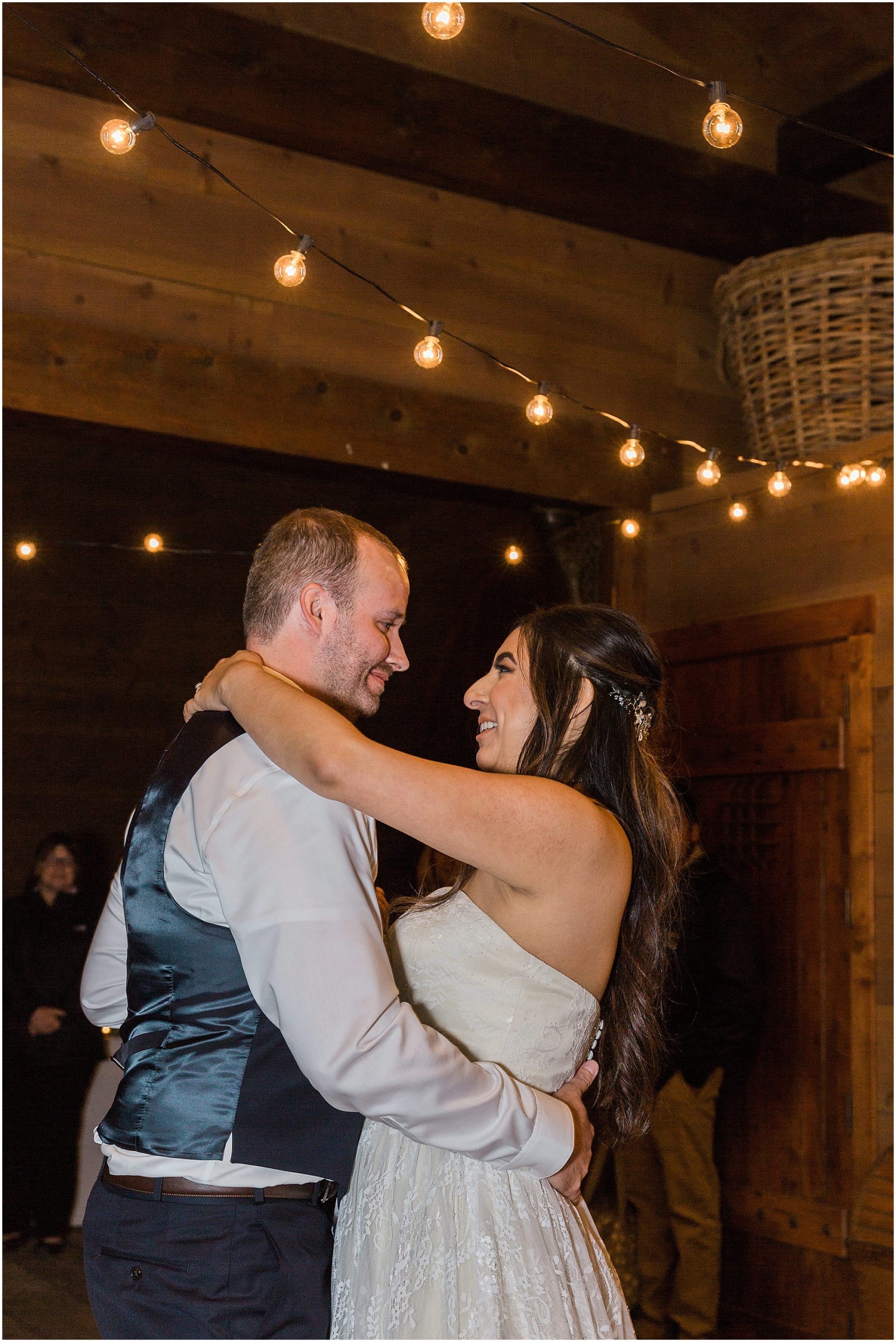 The wedding couple has their first dance under the string lights decorating the Tuscan Stables wedding venue at Ranch at the Canyons in Oregon. | Erica Swantek Photography
