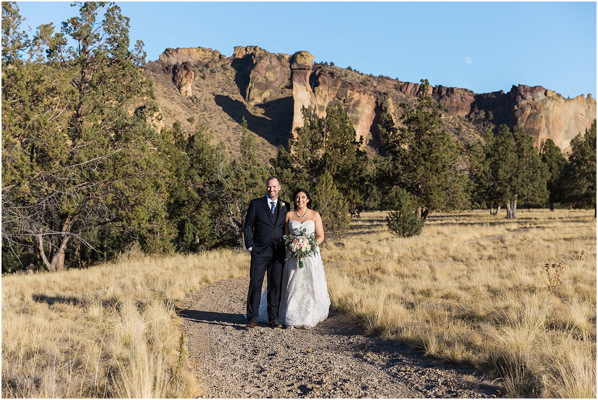 The backside of Smith Rock is visible as a couple poses for their romantic portraits at the Tuscan Stable venue of their Ranch at the Canyons fall wedding in Oregon. | Erica Swantek Photography