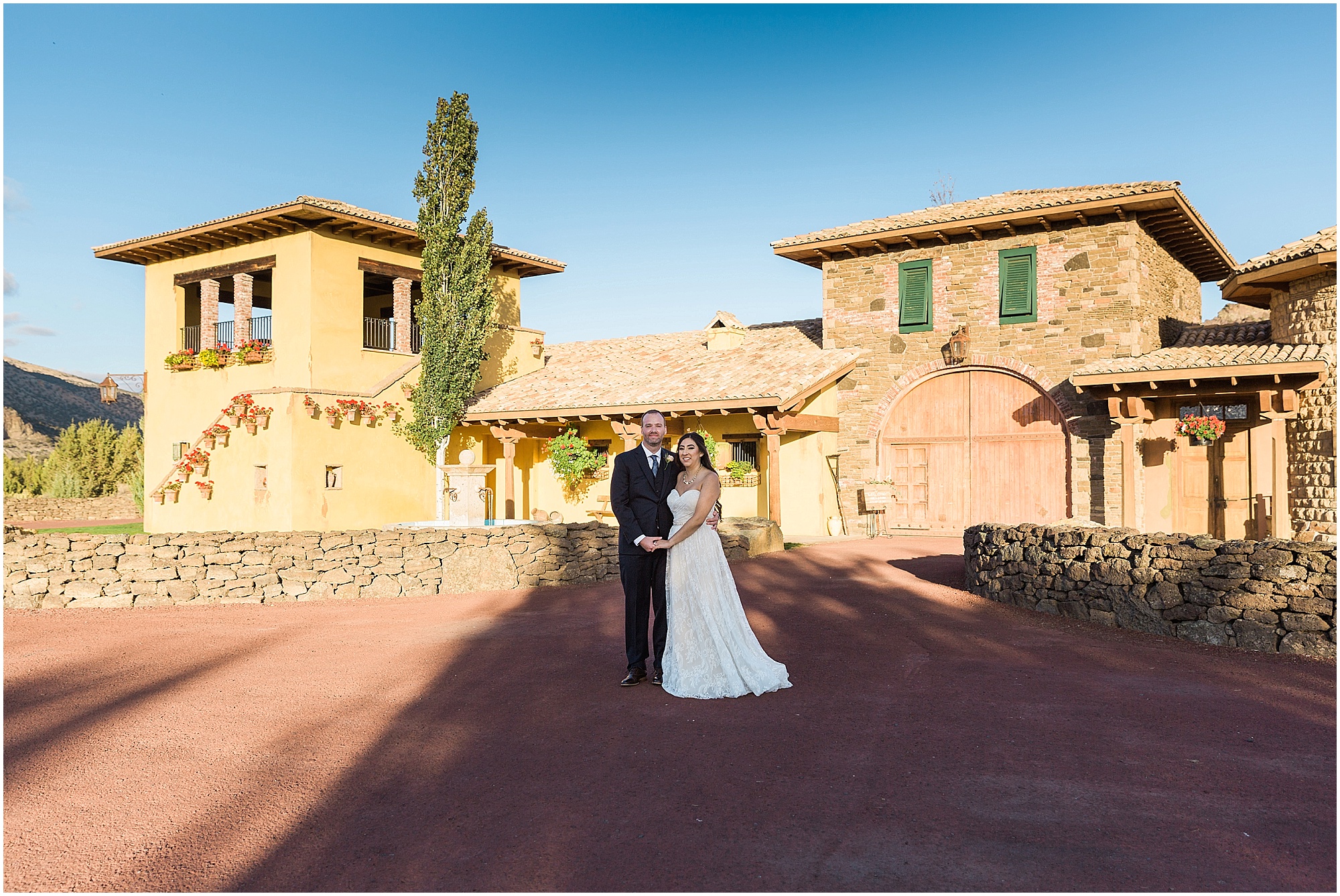 A wedding couple poses in front of the gorgeous Tuscan Stables at Ranch at the Canyons in Terrebonne, OR. | Erica Swantek Photography