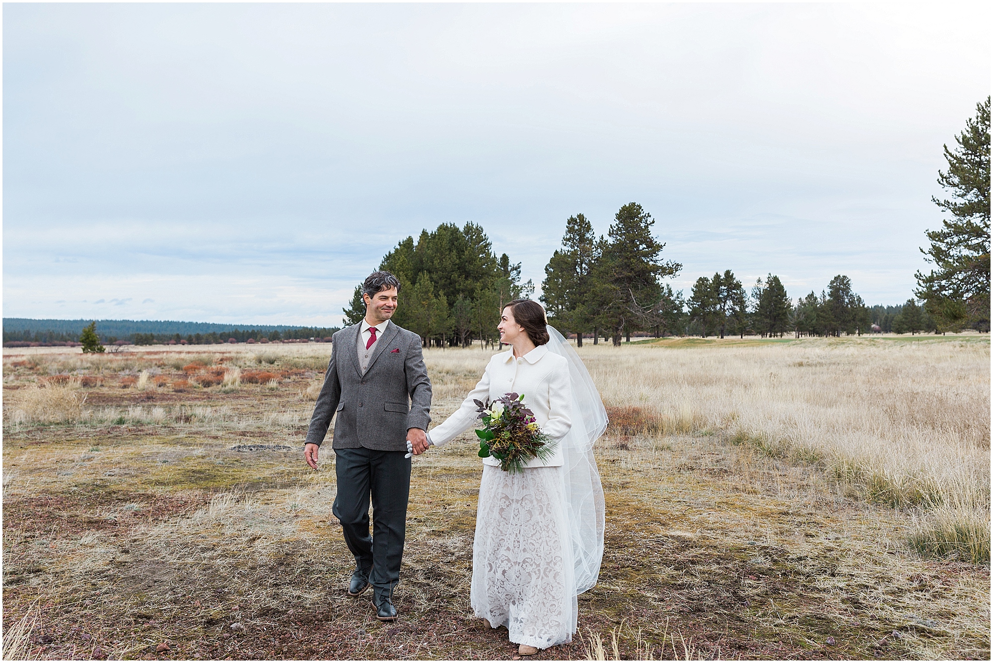 A couple walks through the tall brown grass for their romantic portraits during their Sunriver Resort winter wedding in Oregon. | Erica Swantek Photography