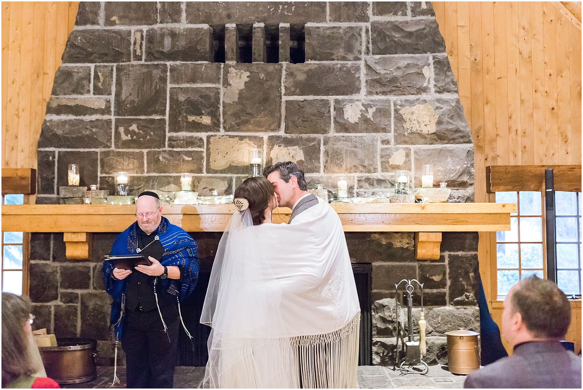 The couple goes in for a kiss at their Sunriver Resort winter wedding at the Fireside Room in Oregon. | Erica Swantek Photography