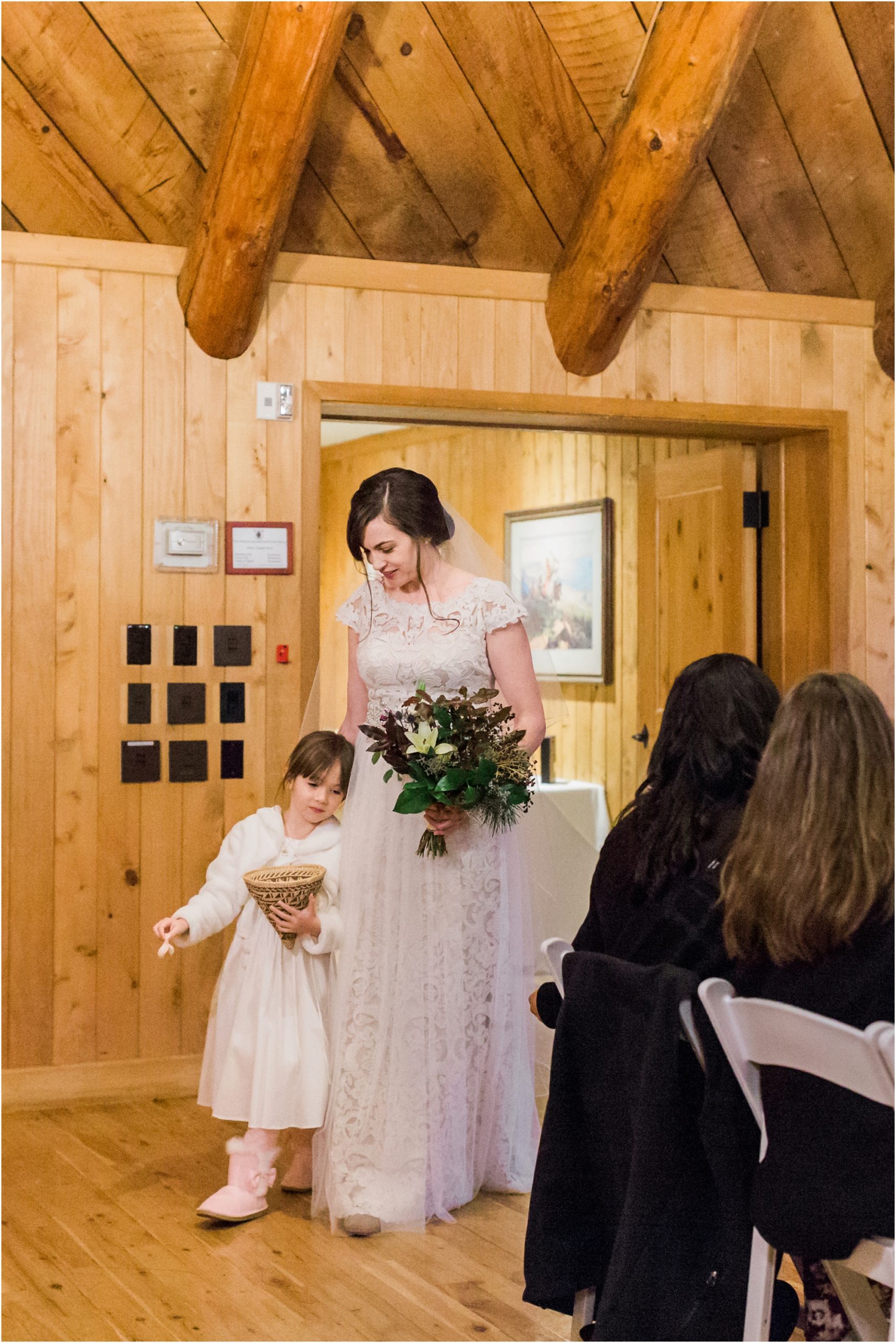 The bride is escorted down the aisle of the gorgeous wooden lodge feel of the Fireside Room at her Sunriver Resort winter wedding in Oregon. | Erica Swantek Photography