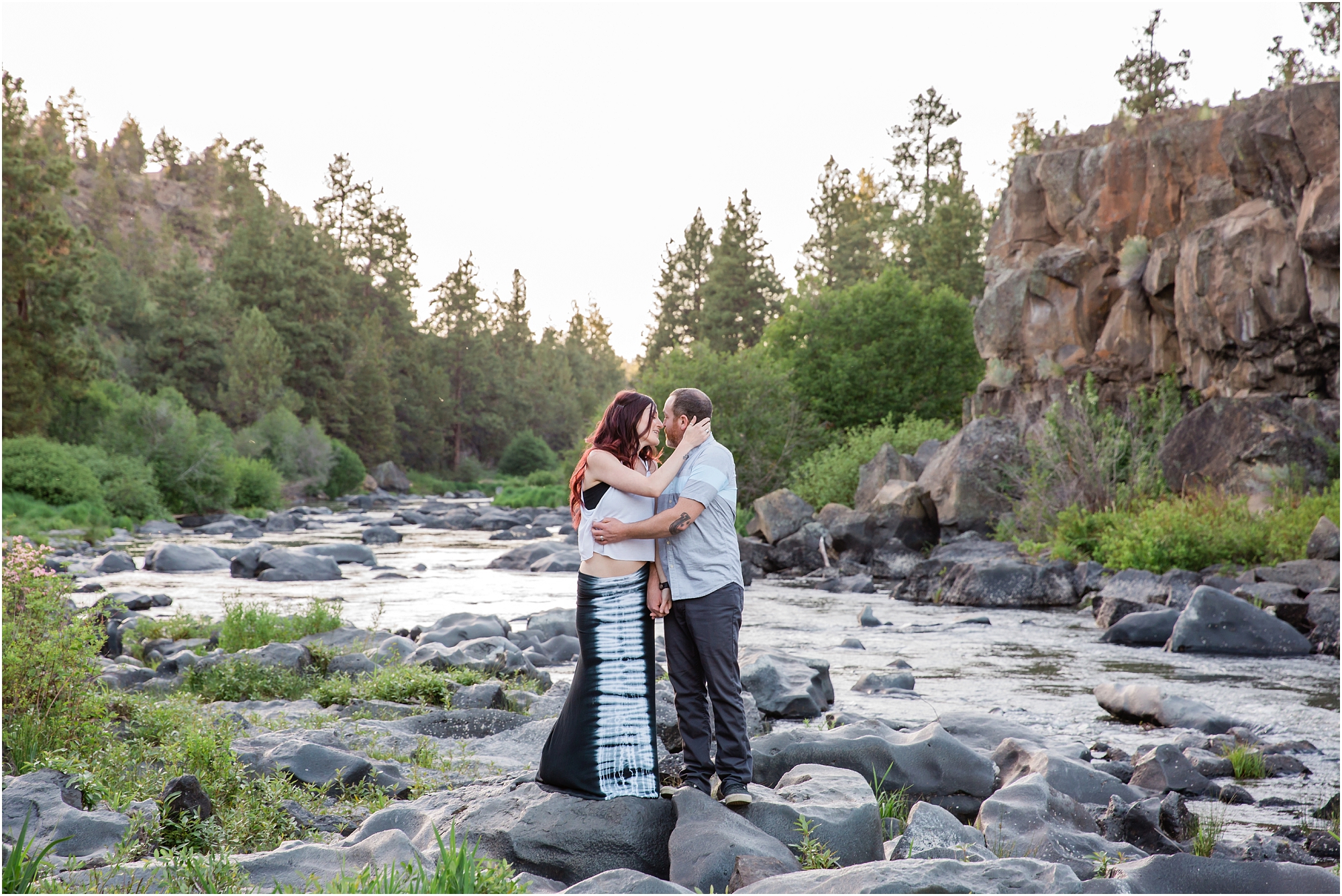 A couple kisses during their engagement session at Sawyer Park along the Deschutes River in Bend, OR. | Erica Swantek Photography
