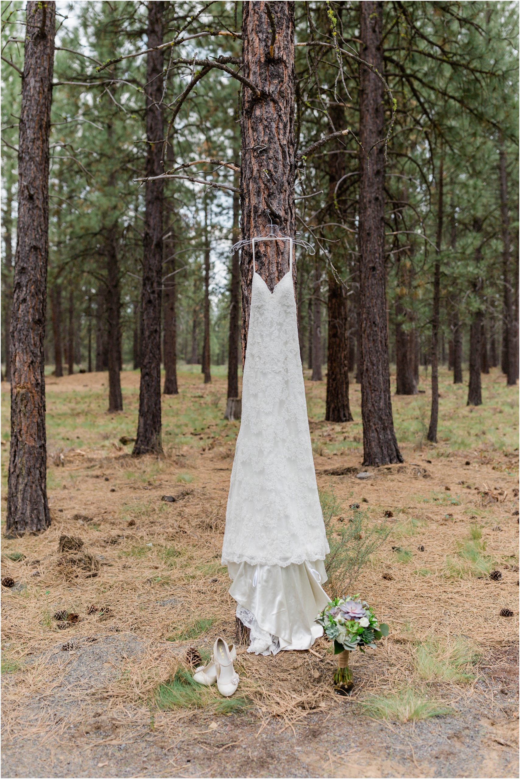 A gorgeous BHLDN wedding gown hangs from a tall pine tree at the High Desert Museum in Bend, OR. | Erica Swantek Photography
