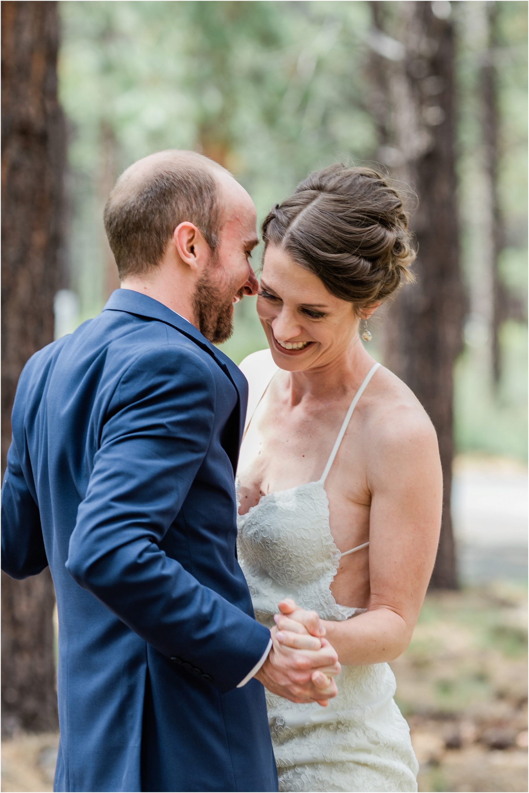 A groom wearing a cobalt blue suit and a bride in a strappy BHLDN gown share a laugh during their first look at the High Desert Museum wedding venue in Bend, Oregon. | Erica Swantek Photography