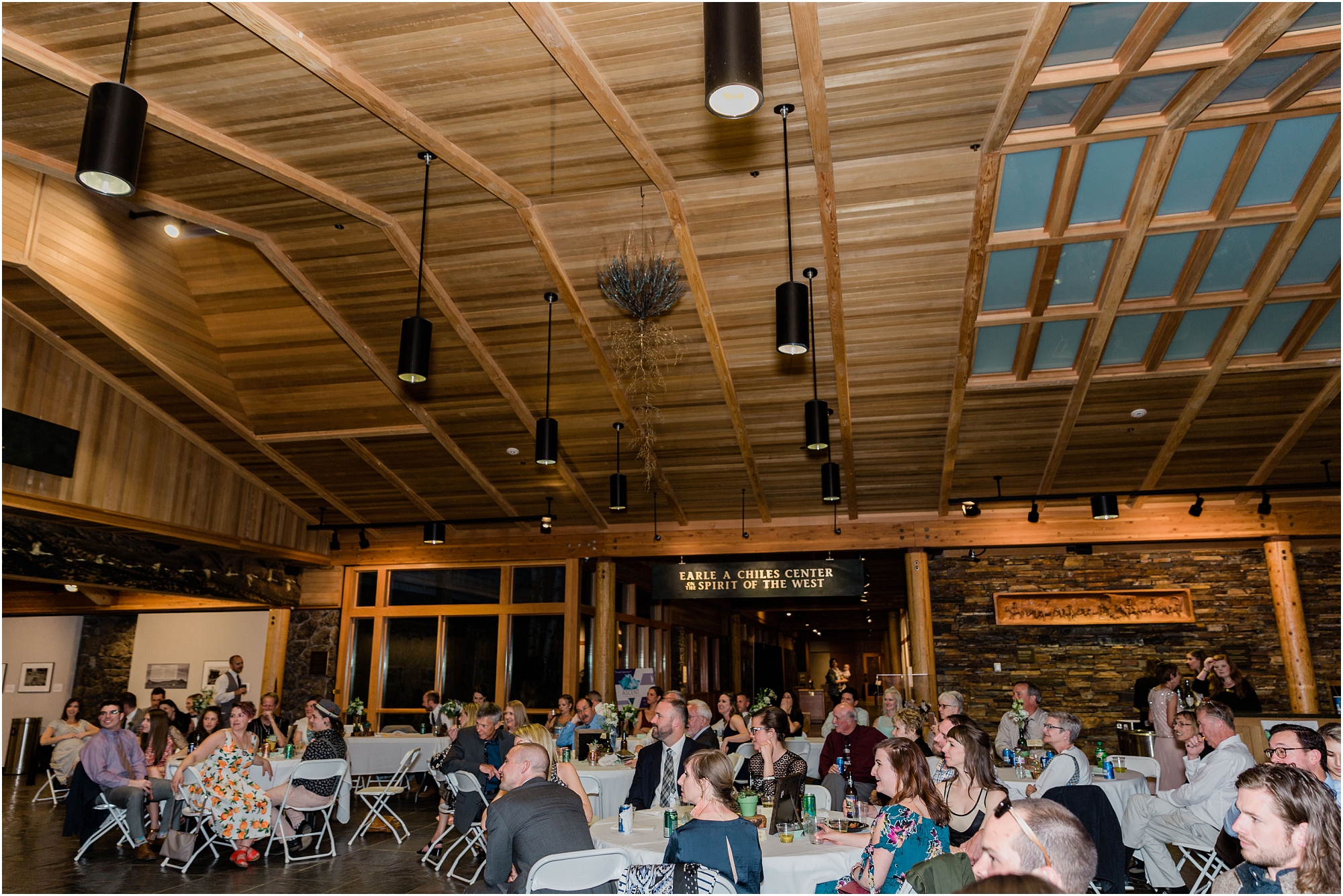 Guests enjoy dinner and toasts in the Schnitzer Entrance Hall of the High Desert Museum wedding venue in Bend, OR. | Erica Swantek Photography