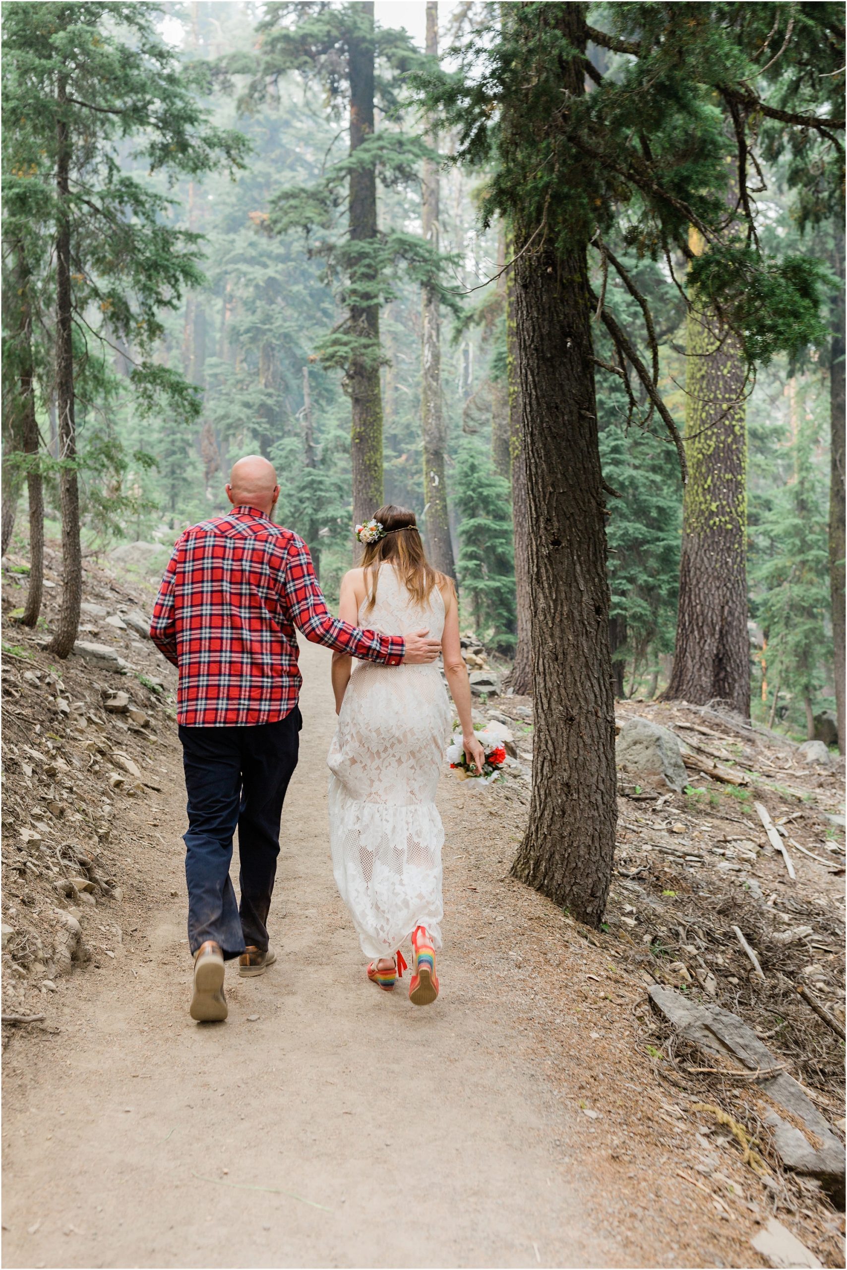 A groom wraps his arm gently around his bride's back as they hike the trail to Plaiknip Falls in Crater Lake National Park near Bend, Oregon. | Erica Swantek Photography