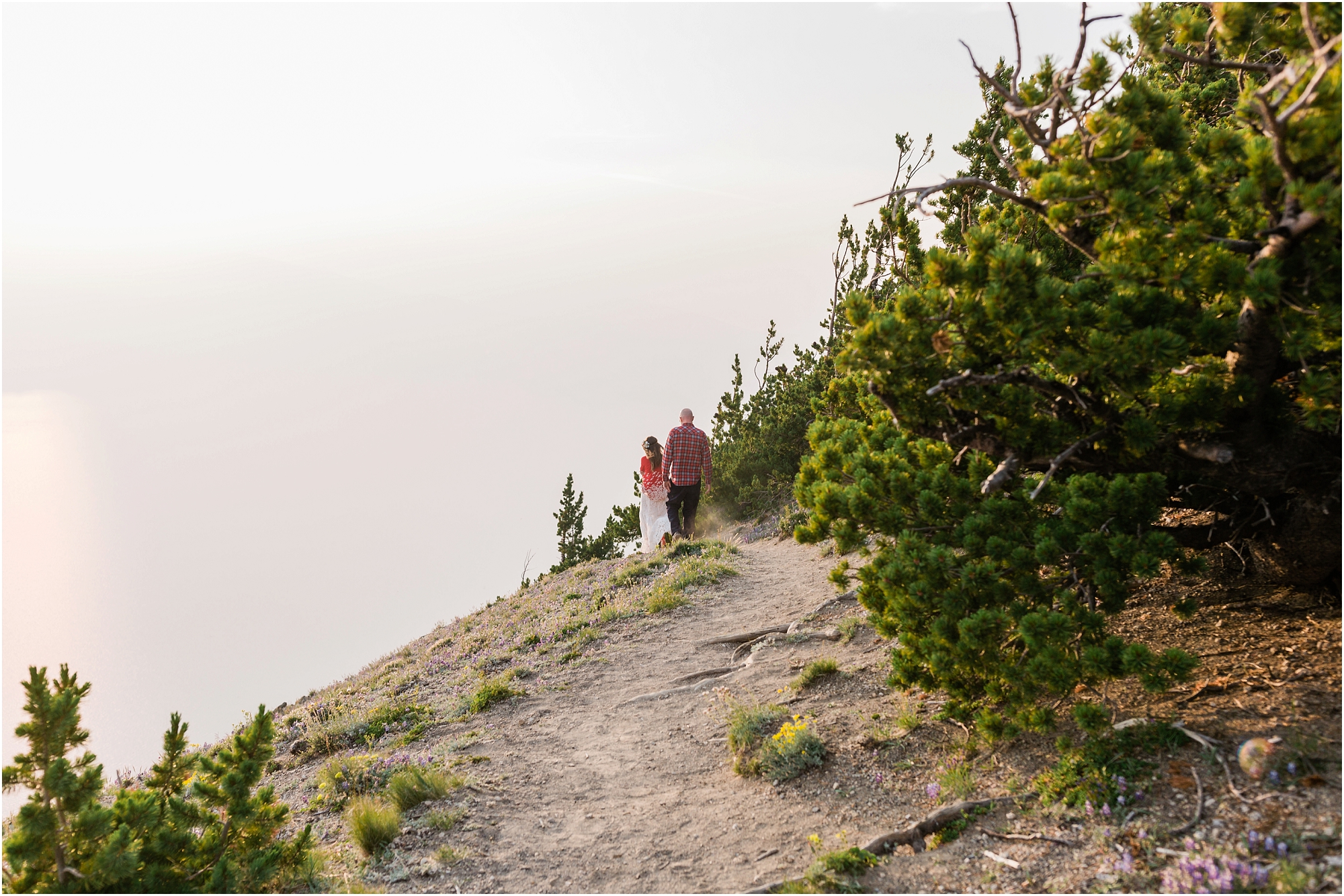 A wedding couple walking out into the abyss as Crater Lake is obscured by wildfire smoke. | Erica Swantek Photography