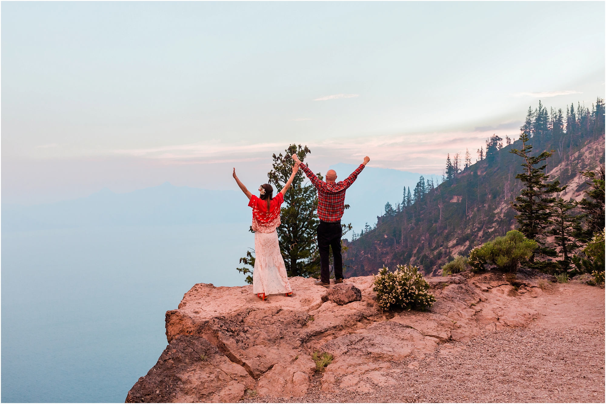 Newlyweds enjoy the magnificent sunset and raise their arms to the sky after their Crater Lake elopement in Oregon. | Erica Swantek Photography