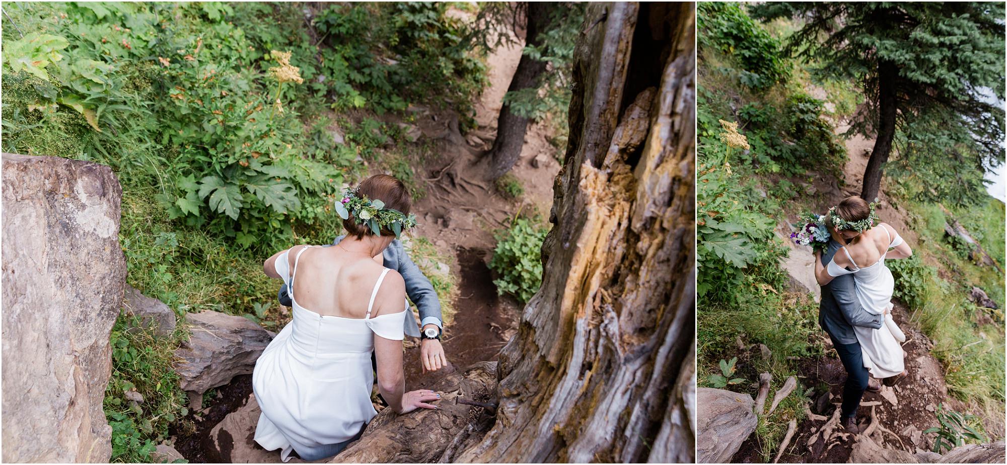 A newly married couple hikes down the trail climbing down large tree roots for photos at their Tumalo Falls elopement in Bend, Oregon. | Erica Swantek Photography