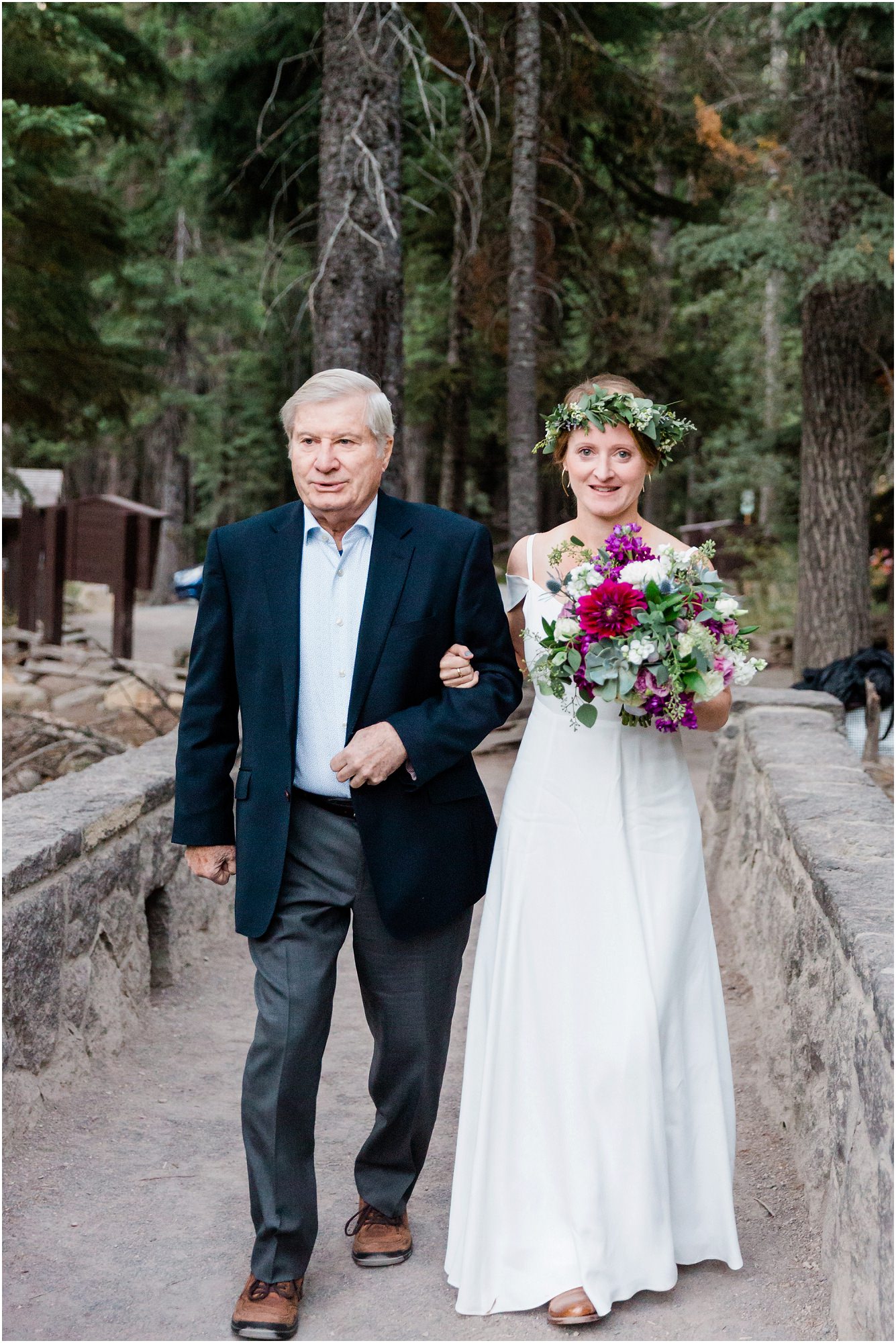 A bride wearing a floral crown is escorted by her father at her Tumalo Falls elopement in Bend, Oregon. | Erica Swantek Photography