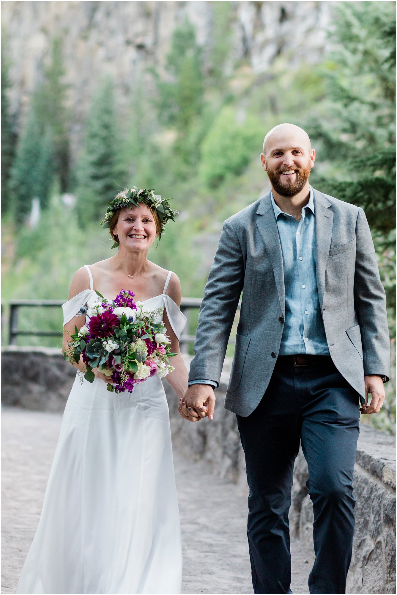A bride wearing a floral crown and a gorgeous succulent bouquet is smiling ear to ear as she walks with her groom after saying their wedding vows at this waterfall elopement in Bend, Oregon. | Erica Swantek Photography