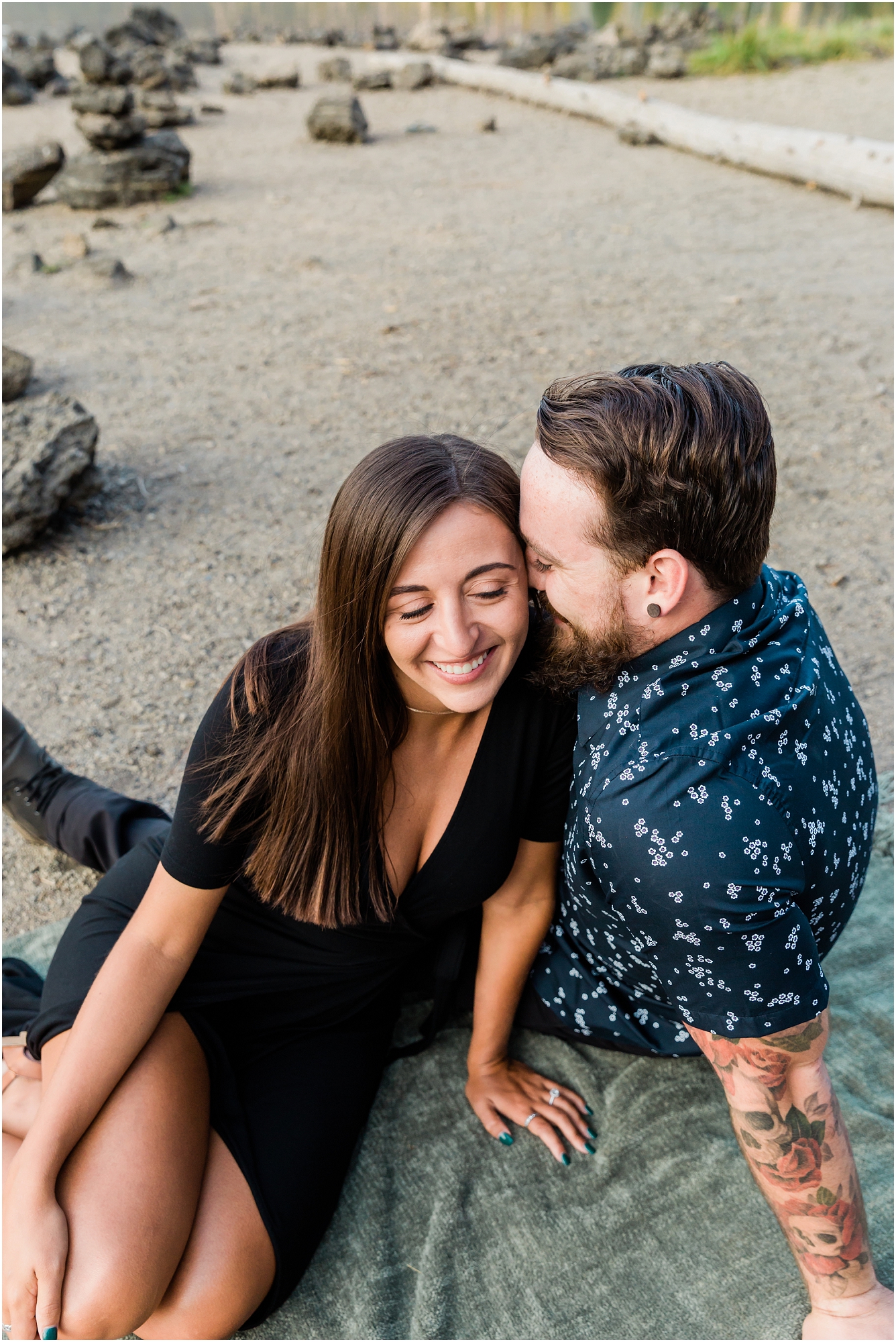 A tattooed guy whispers in the ear of his gorgeous woman at their Sparks Lake engagement photo session near Bend, Oregon. | Erica Swantek Photography