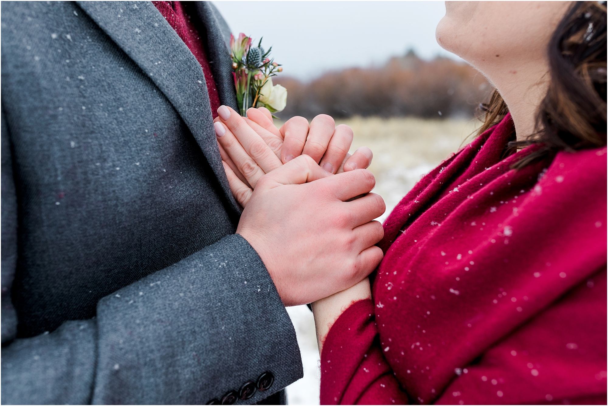 A gorgeous couple in red, burgundy and gray hold hands after their outdoor Central Oregon winter elopement during a snowstorm near Five Pine Lodge in Sisters. | Erica Swantek Photography