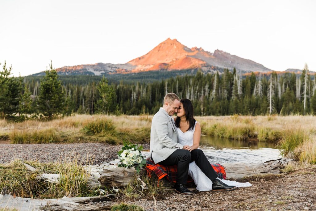 bride and groom sitting on a dry tree during their elopement in bend