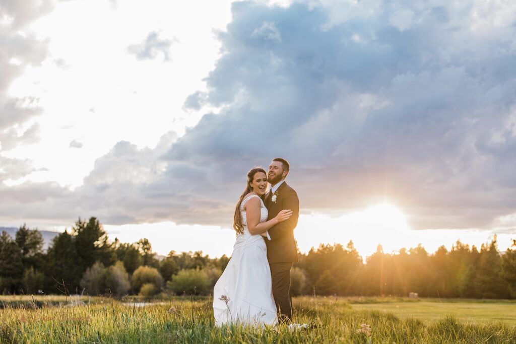 bride and groom hugging in a sunlit field during their black butte ranch wedding