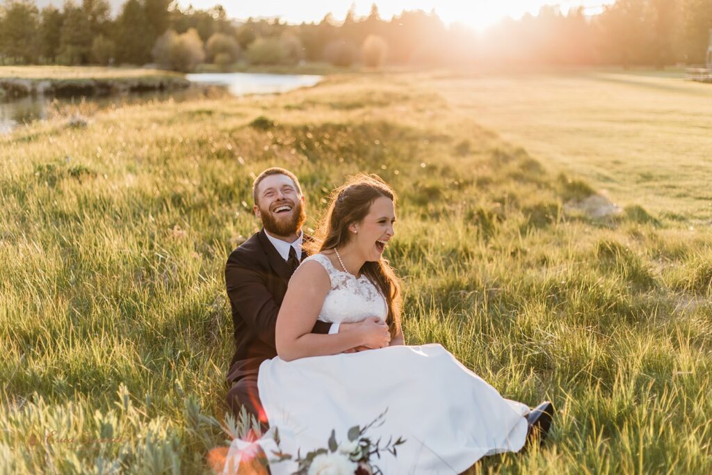bride and groom sitting in a sunlit field during their black butte ranch wedding