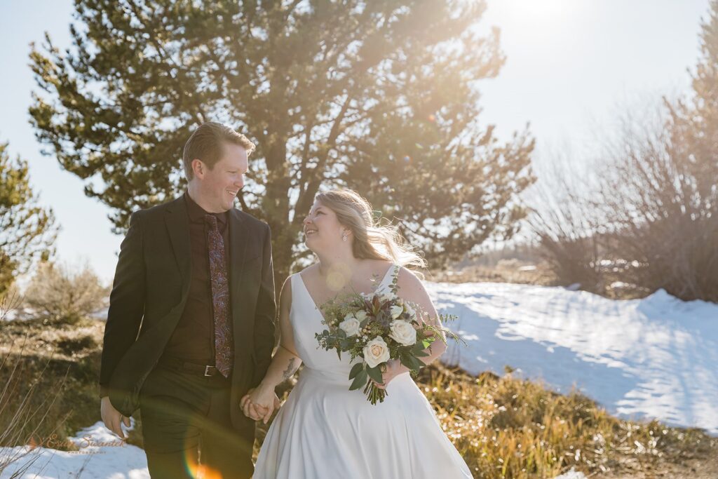 bride and groom walking hand in hand through the snow during their elopement in sunriver, oregon
