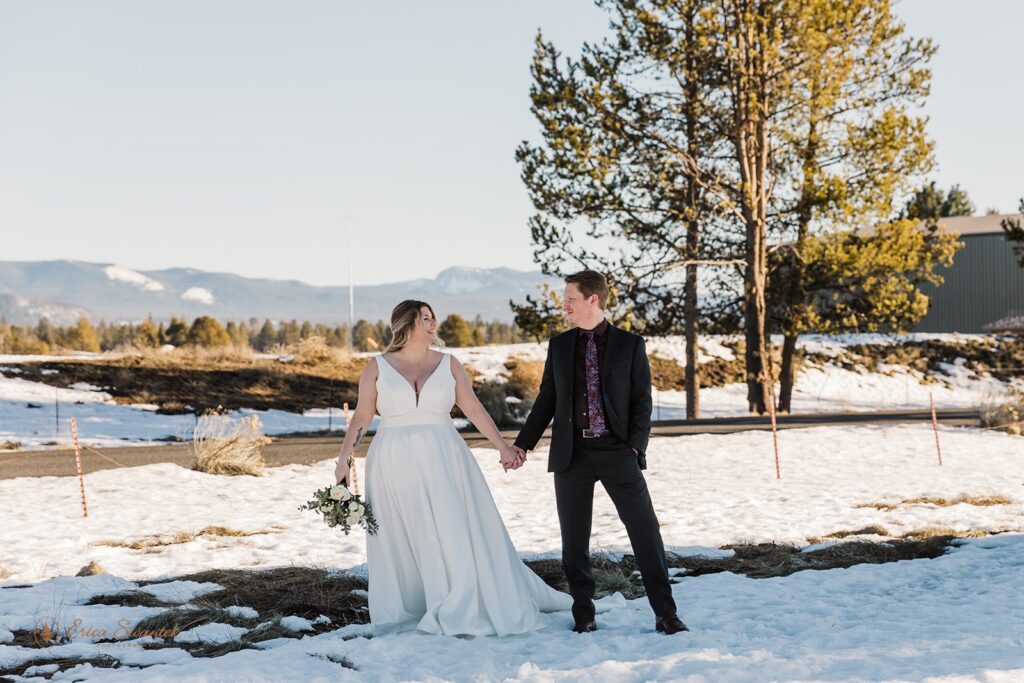bride and groom walking hand in hand through the snow during their elopement in sunriver, oregon