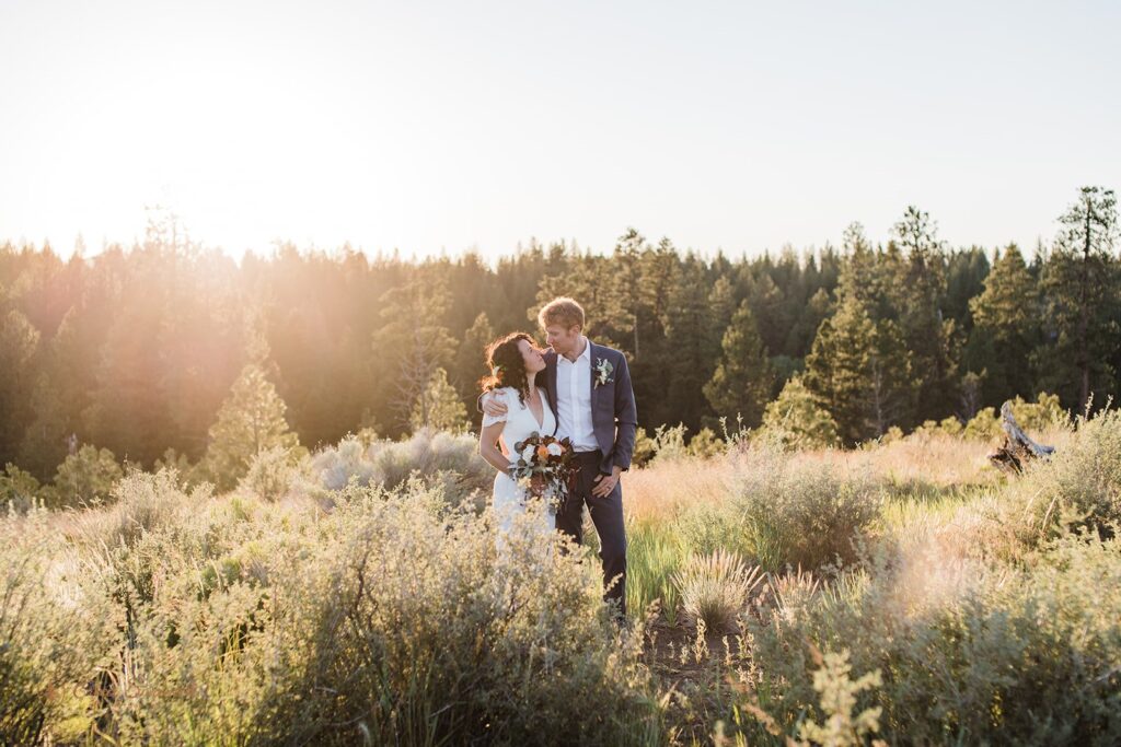 bride and groom in a lush sunlit field during their bend oregon elopement day