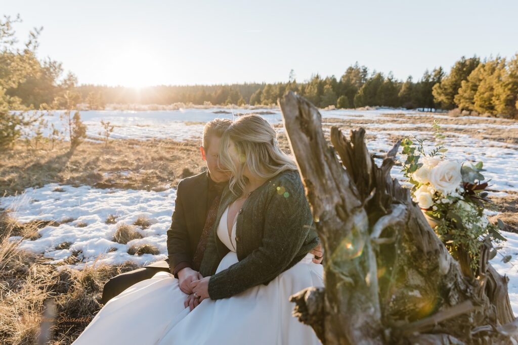 bride and groom sitting on a dry wood during their elopement in sunriver, oregon