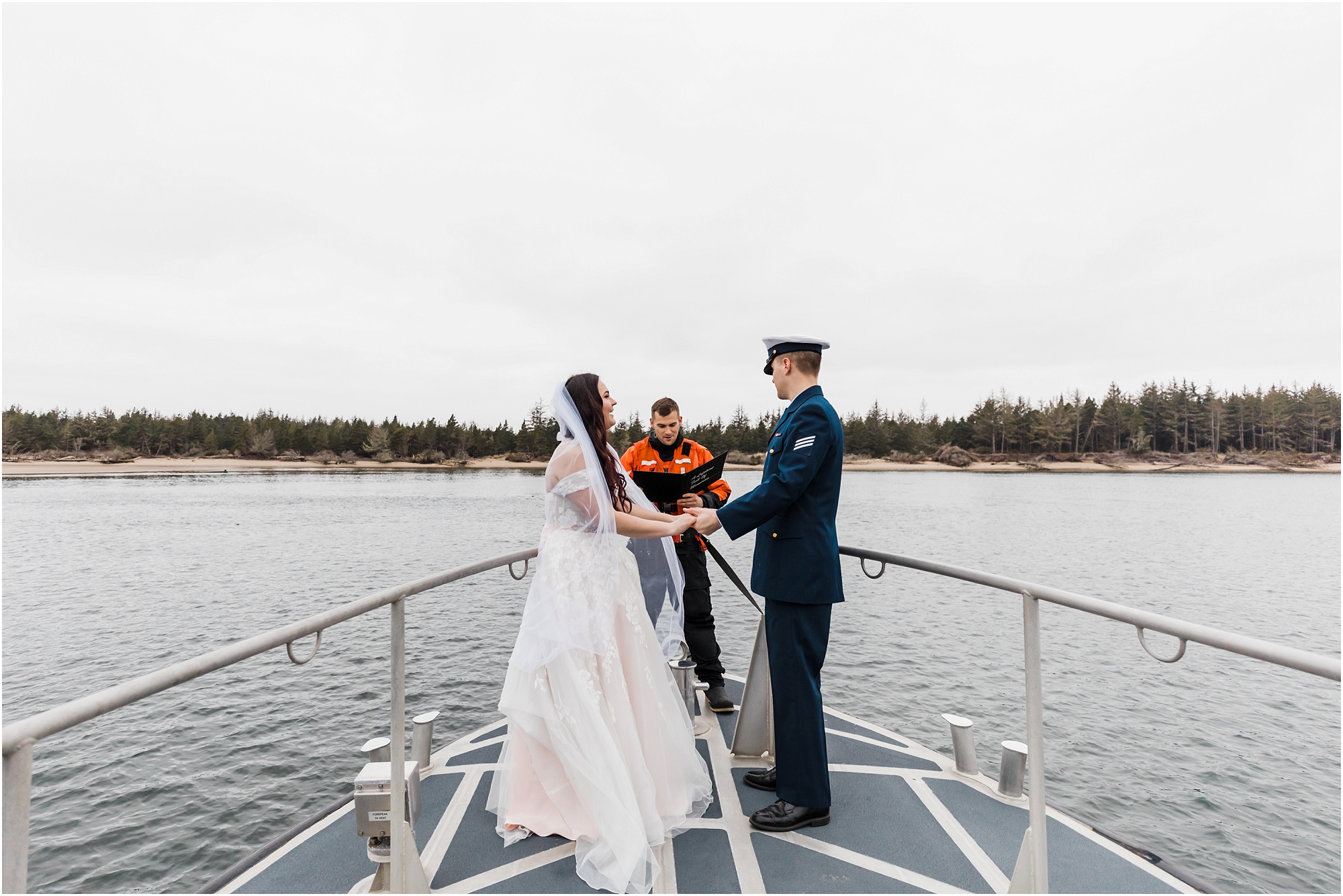 A groom wearing his navy coast guard uniform, holds his bride's hands, as they say their vows on the bow of a US Coast Guard ship in Winchester Bay for their adventure Oregon elopement. | Erica Swantek Photography