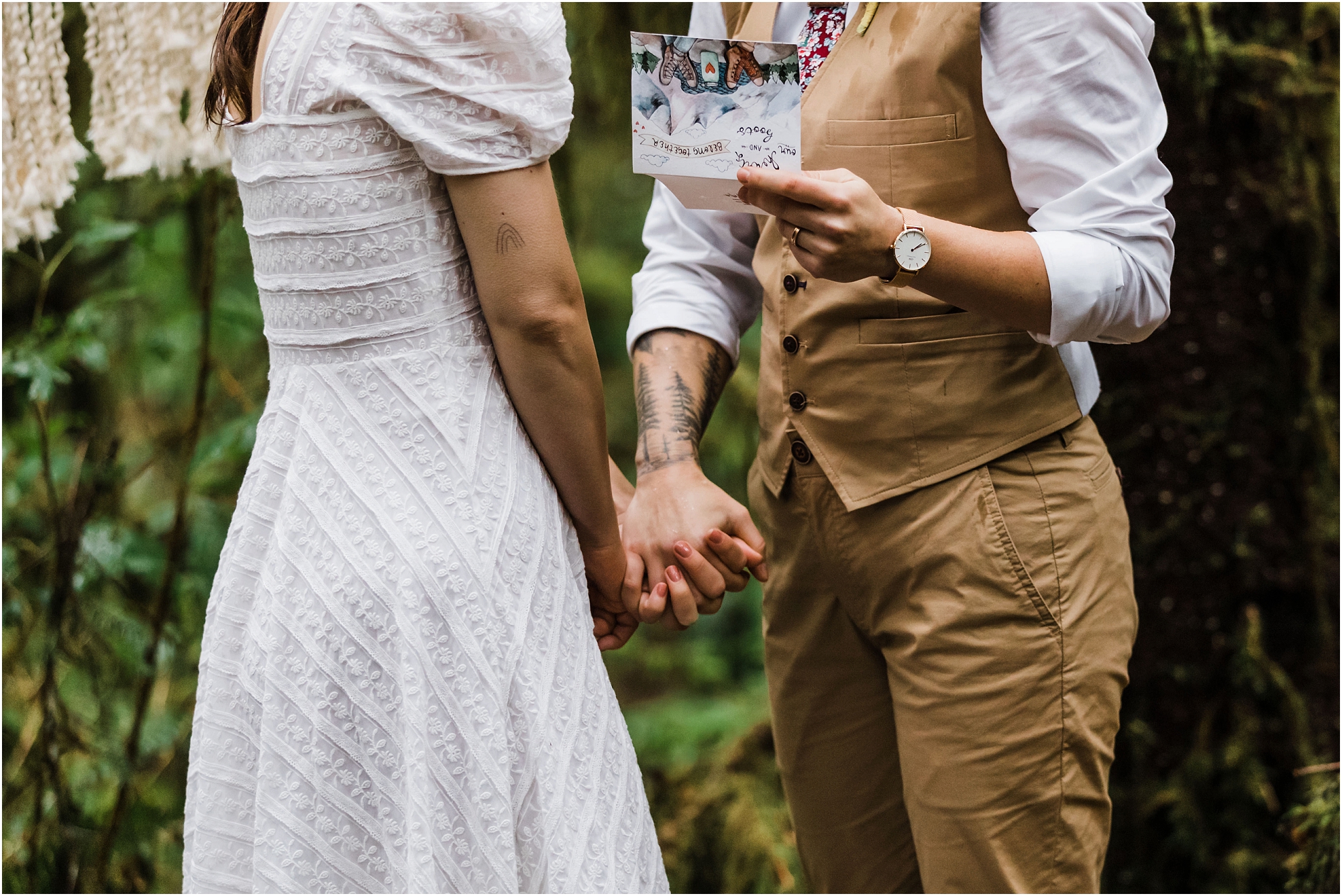 A LGBTQ+ couple holds hands as they read their vows to each other on the Drift Creek Falls trail for their PNW hiking adventure elopement in Oregon. | Erica Swantek Photography