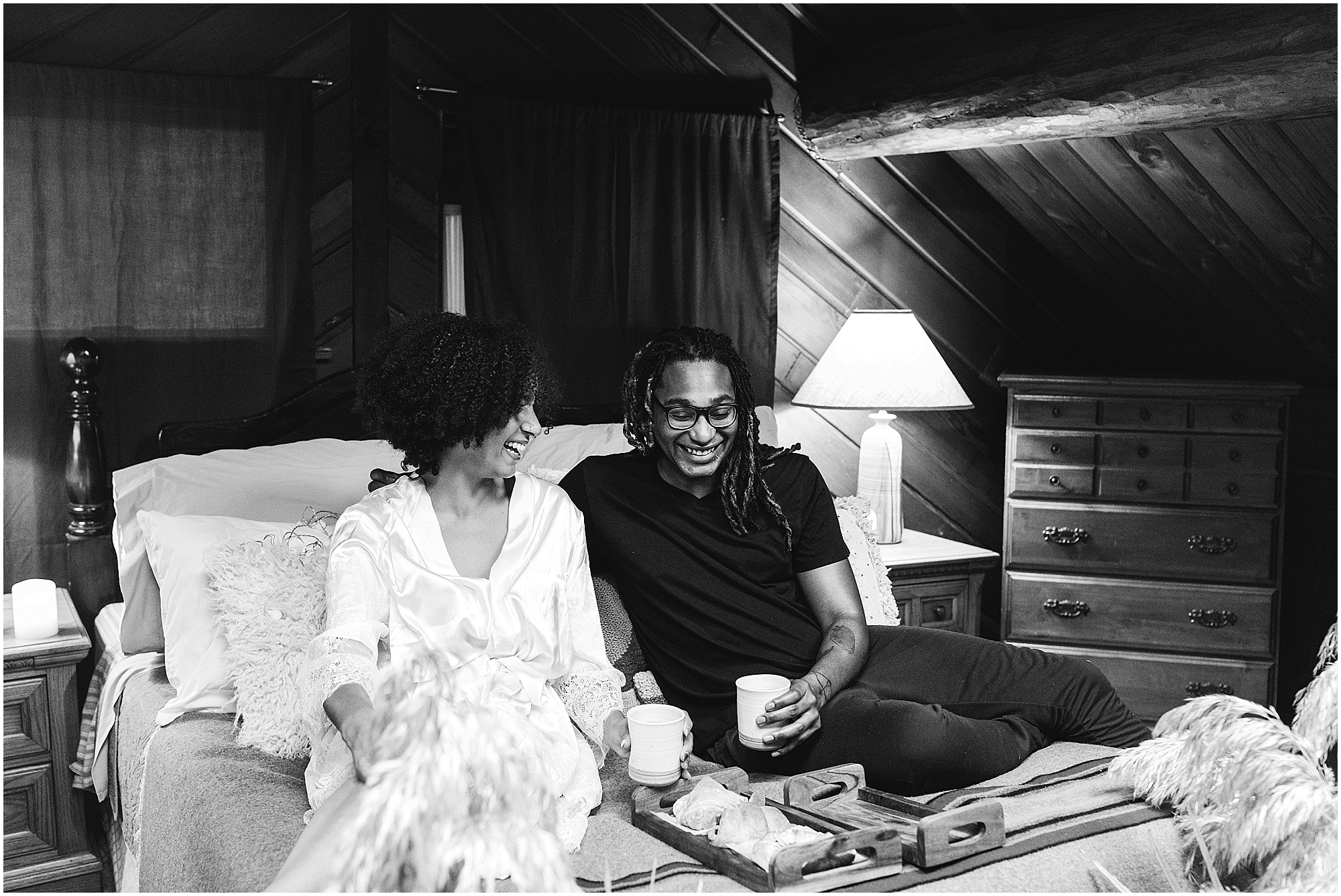 A black and white image of a BIPOC couple laughing and sharing coffee in their Oregon Coast cabin near Lincoln City. | Erica Swantek Photography