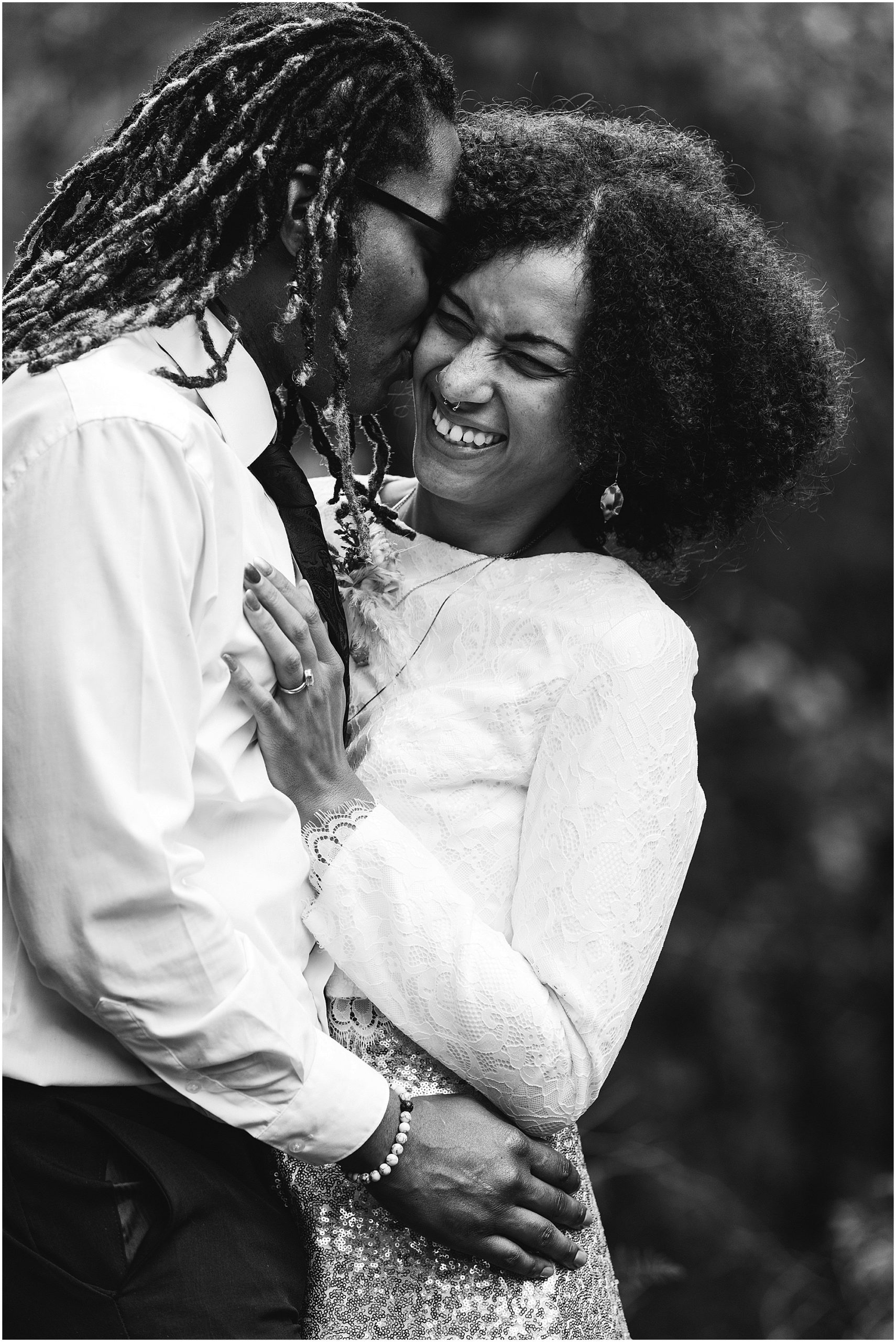 A beautiful black and white image of a bride laughing as her groom nestles into her cheek on their Oregon Coast elopement day. | Erica Swantek Photography