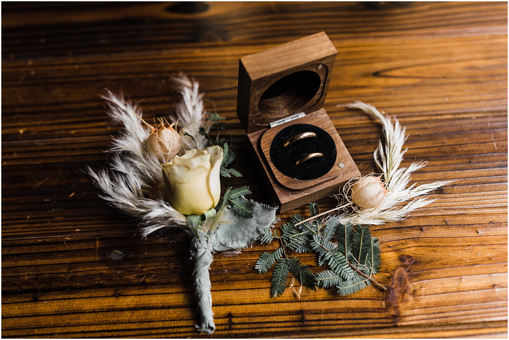 A yellow rose with tan grass boutonniere and simple gold rings in a wooden ring box for an adventure elopement on the Oregon Coast. | Erica Swantek Photography