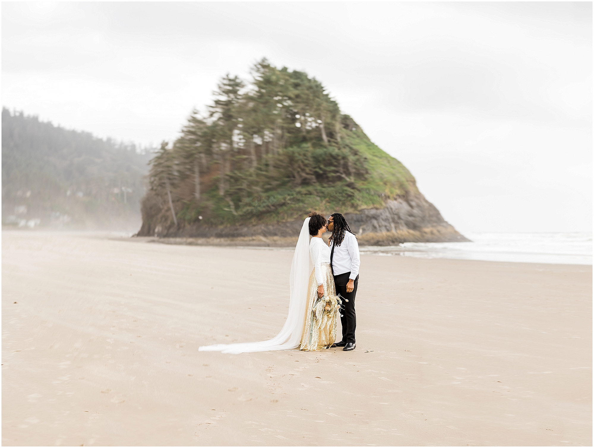 A beautiful couple stands in front of Proposal Rock in Neskowin, Oregon for their Oregon Coast elopement on the beach. | Erica Swantek Photography