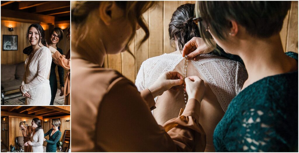 A bride gets ready in the bunkhouse while her girlfriends help button the back of her lace gown at her Silcox Hut winter wedding in Oregon. 
