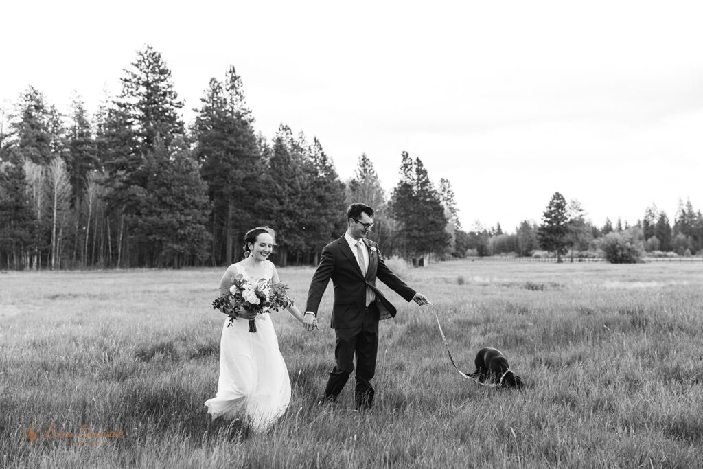 A couple wanders through a meadow in Oregon with their dog.