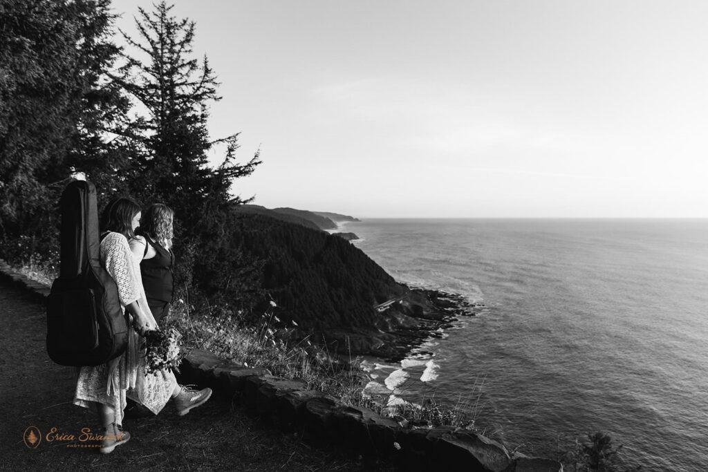 A couple stands on a cliff overlooking the Oregon Coast.