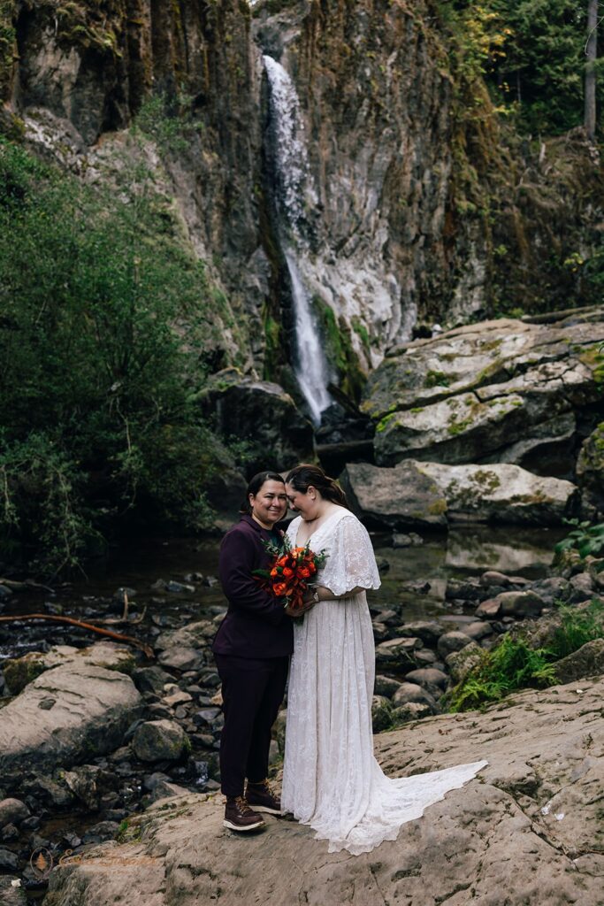 lgbtq couple during their forest elopement in Oregon with waterfall in the backdrop