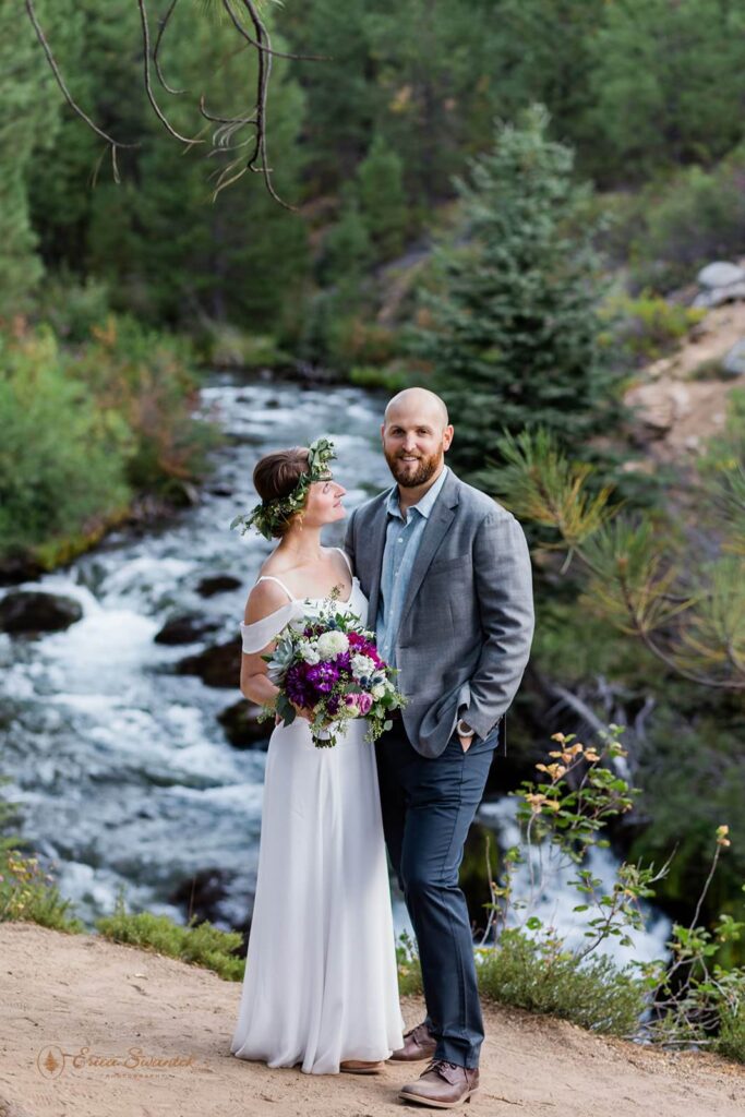 A couple stands near a waterfall in Oregon during their intimate wedding.