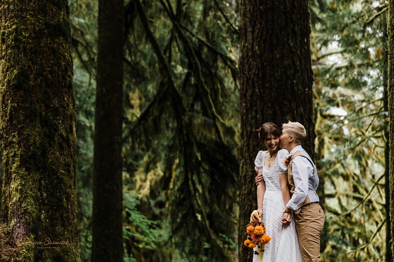 A couple kisses in tall pines in Oregon.