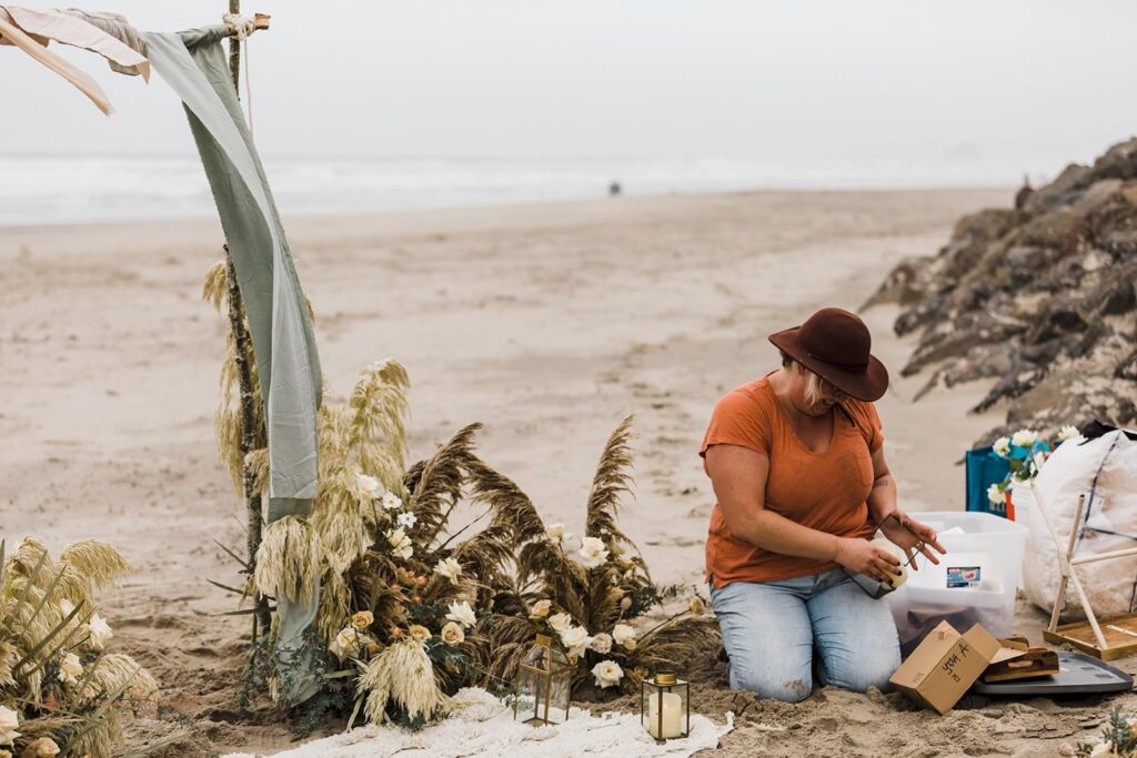A wedding vendor assists with setting up a beach ceremony in Oregon.
